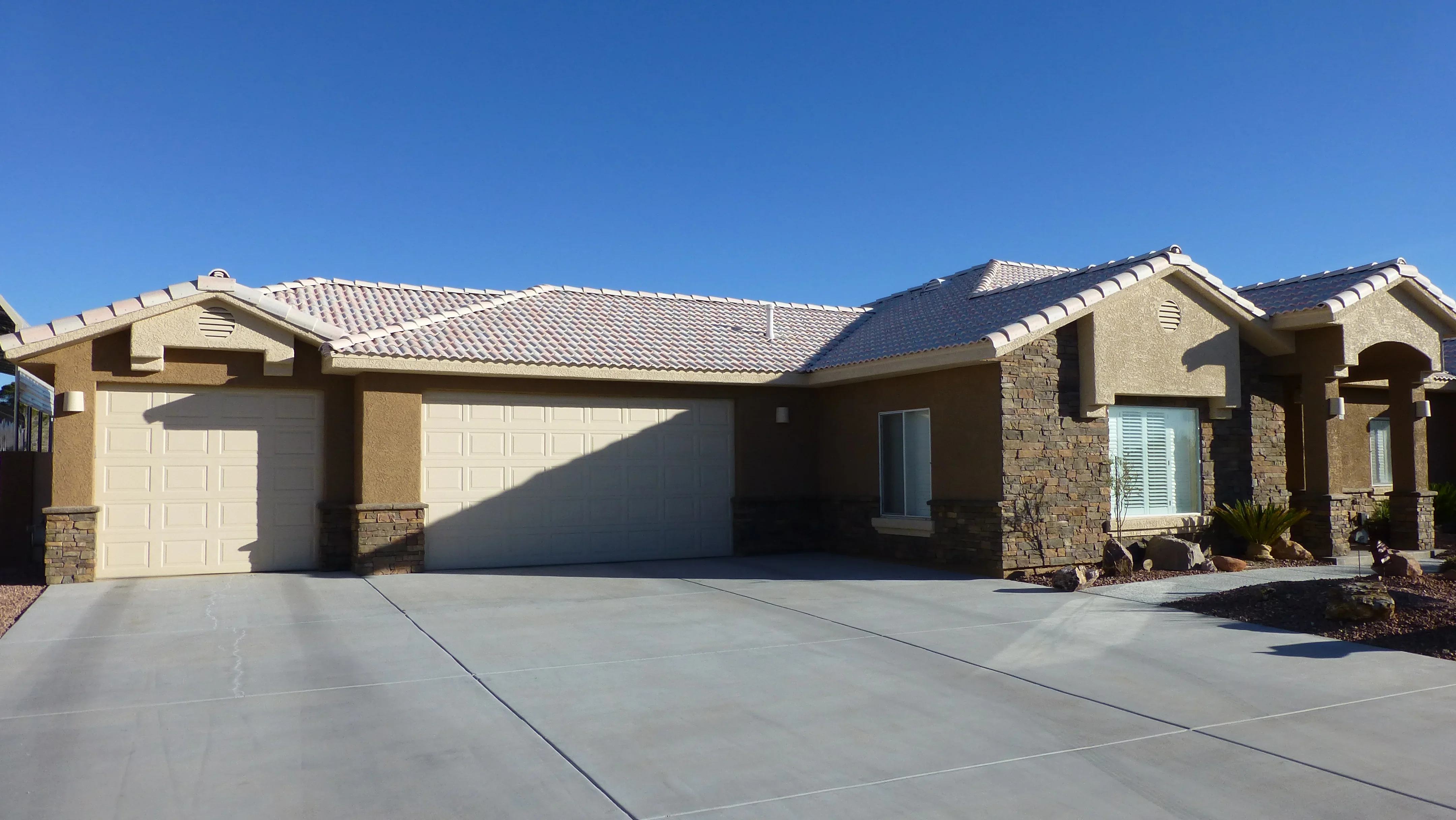 Finished concrete driveway with control joints in front of modern home with stucco and stone