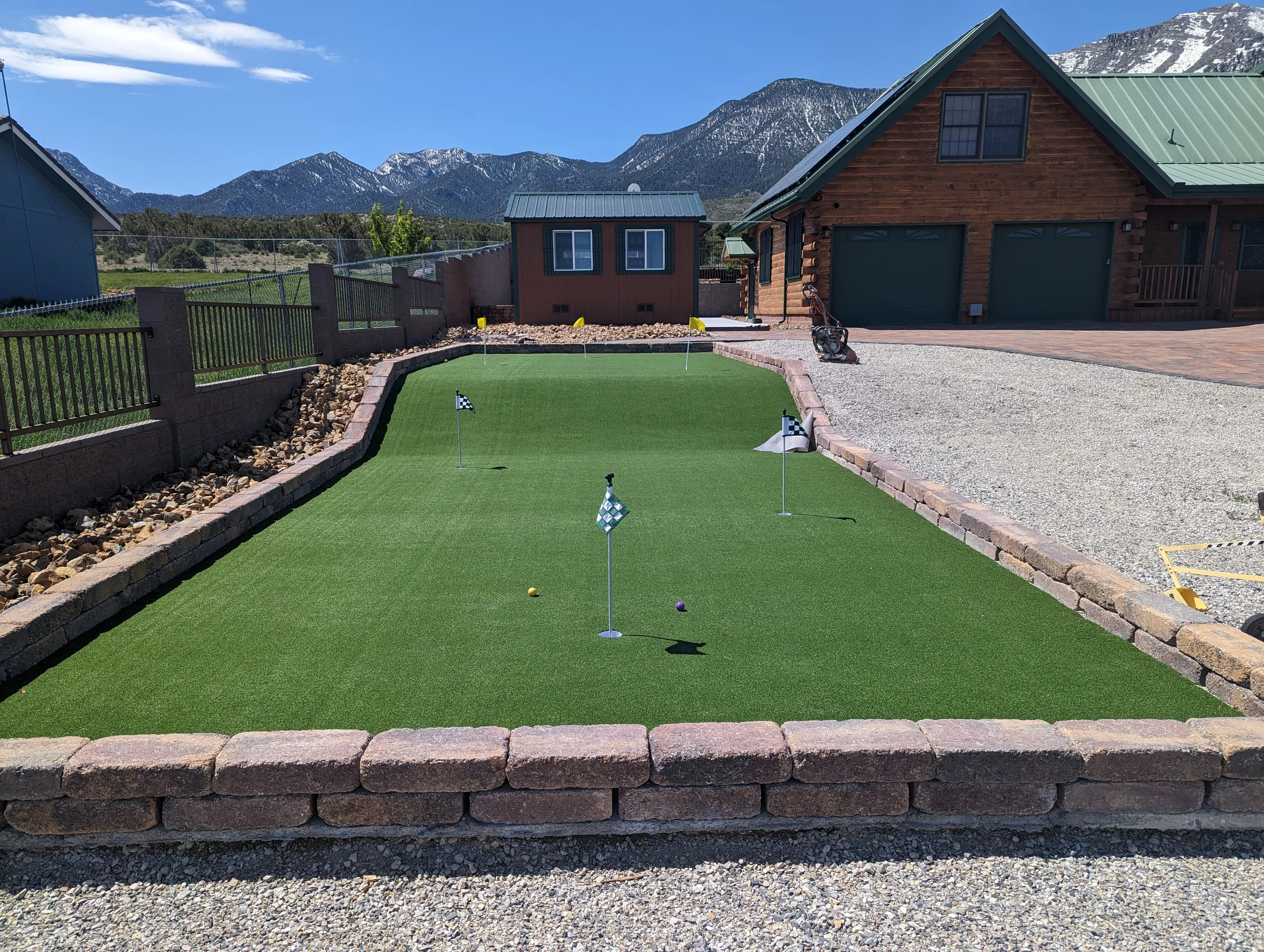 Synthetic putting green with brick border and mountain backdrop