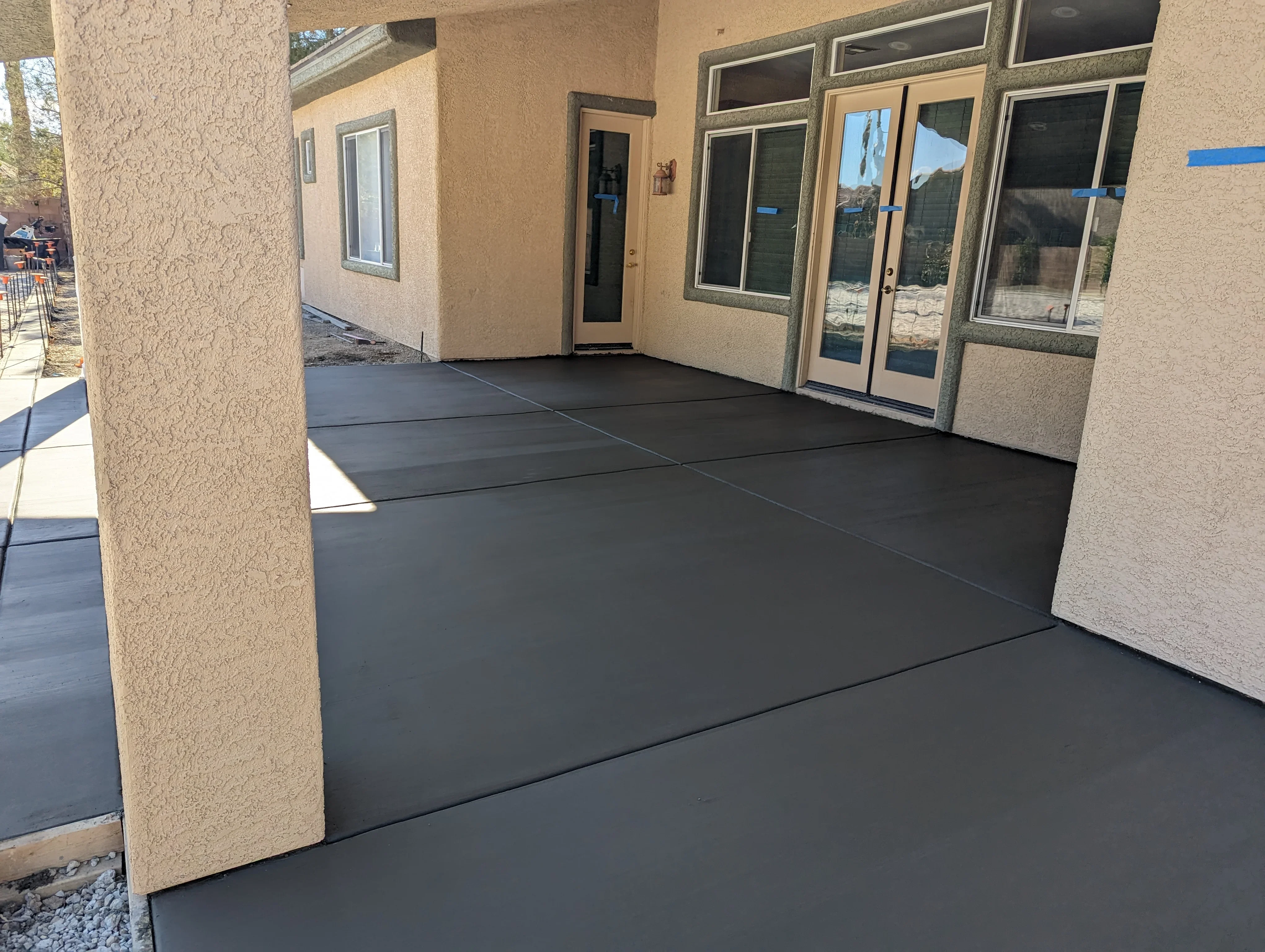 Dark gray concrete patio with decorative scoring lines and stucco building exterior