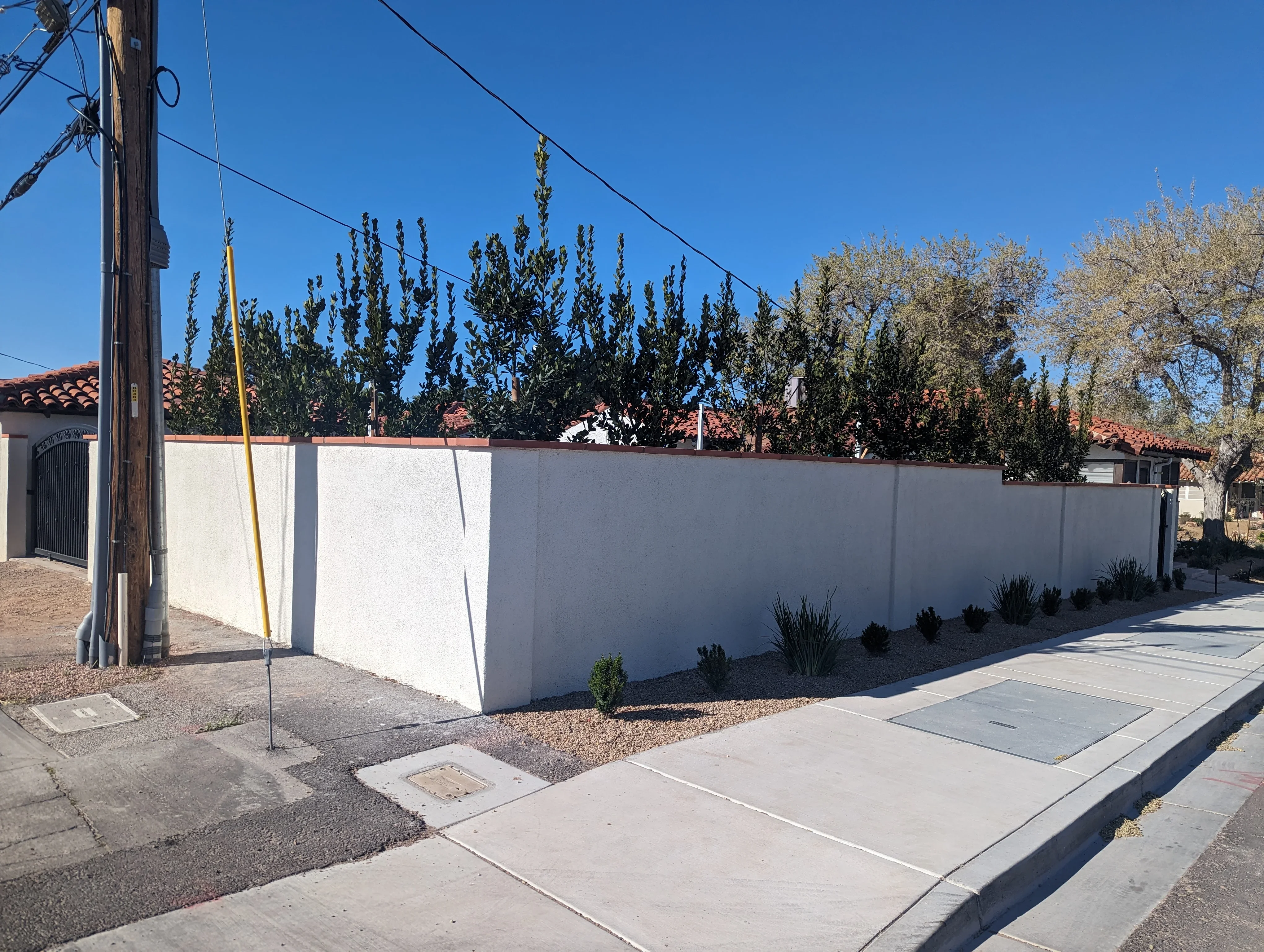 White concrete perimeter wall with gravel base and desert plants in Las Vegas