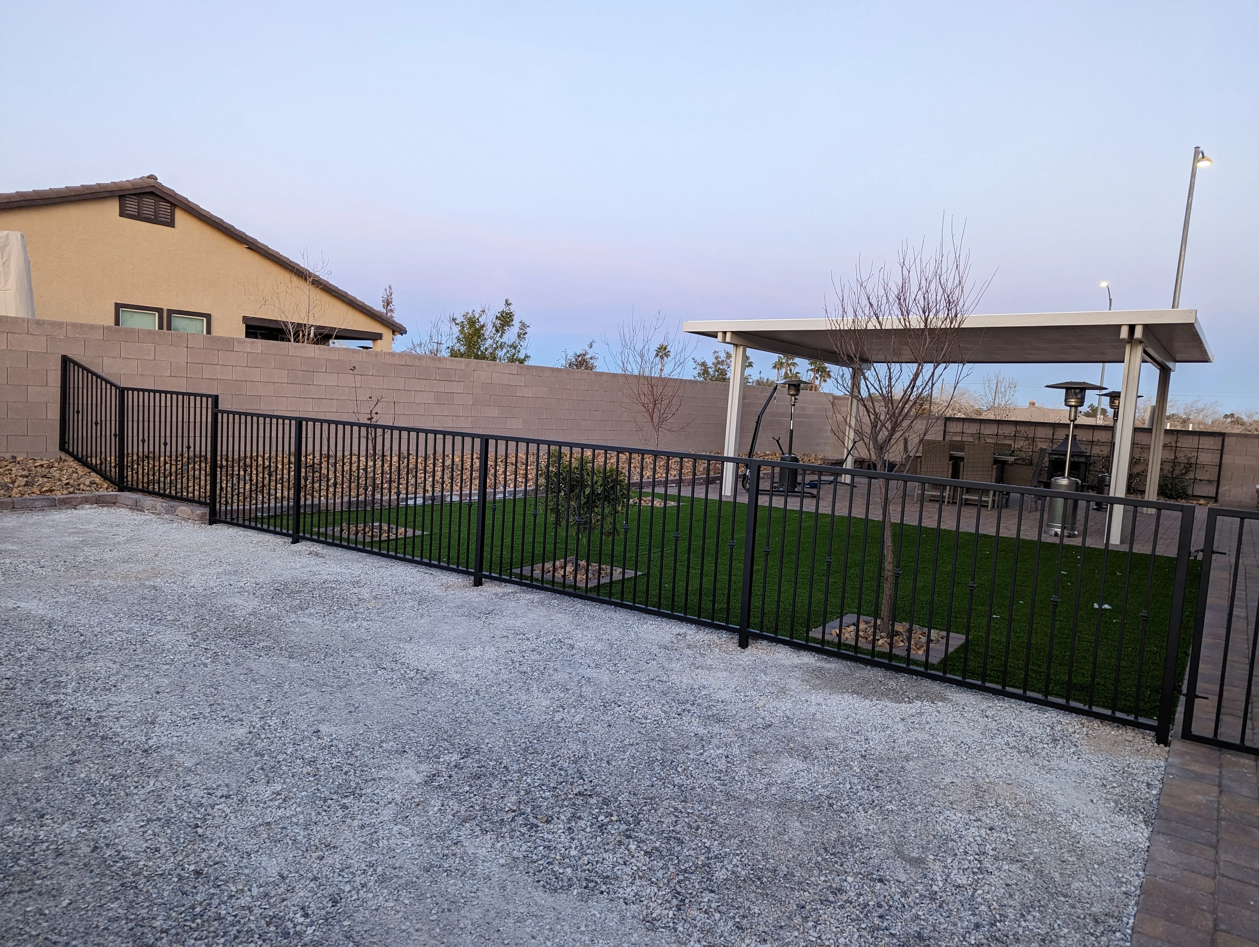 Gravel patio with black metal railing and pergola structure in Las Vegas