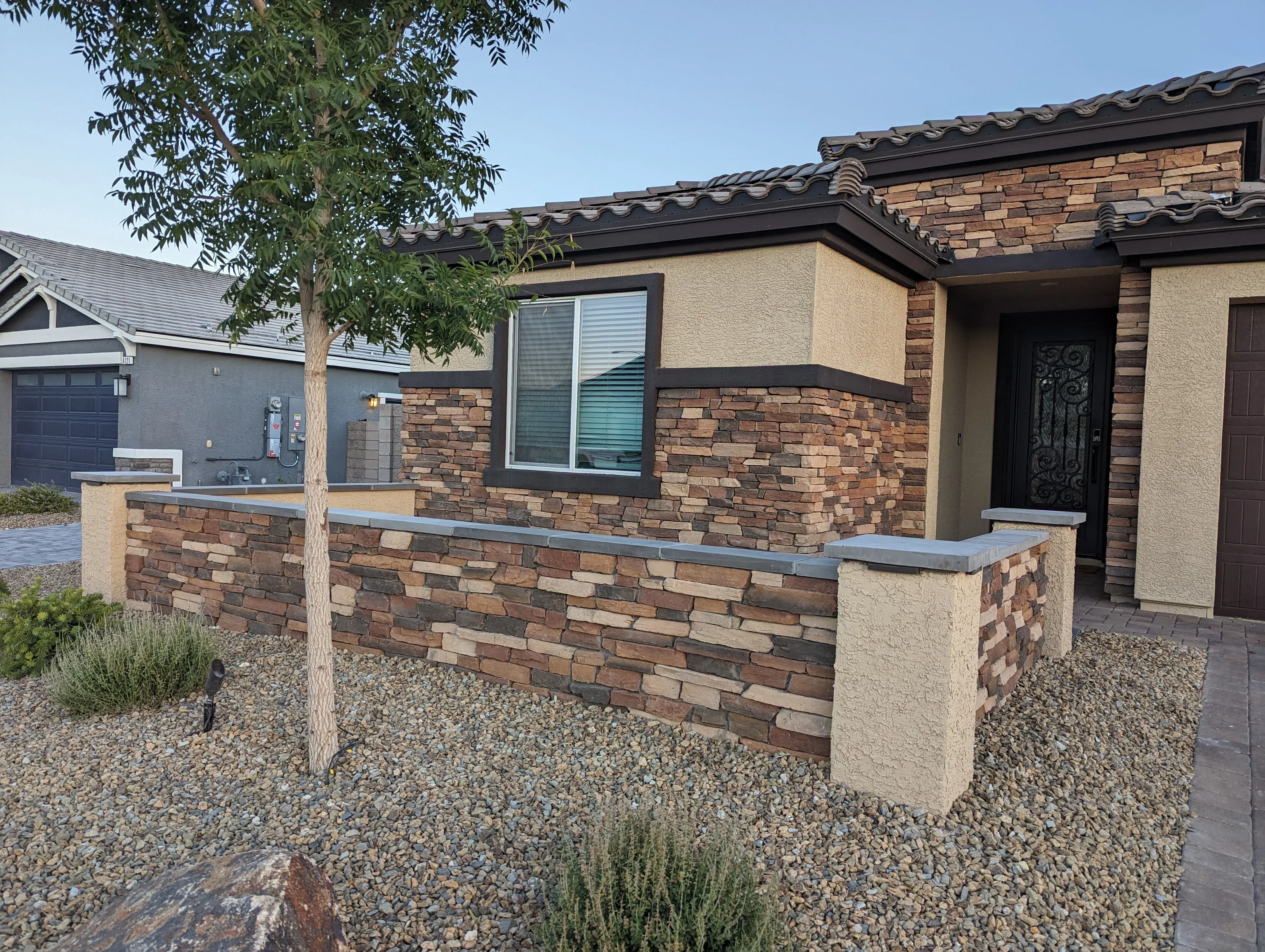Modern home courtyard with stacked brick walls, stucco trim, and gravel landscaping