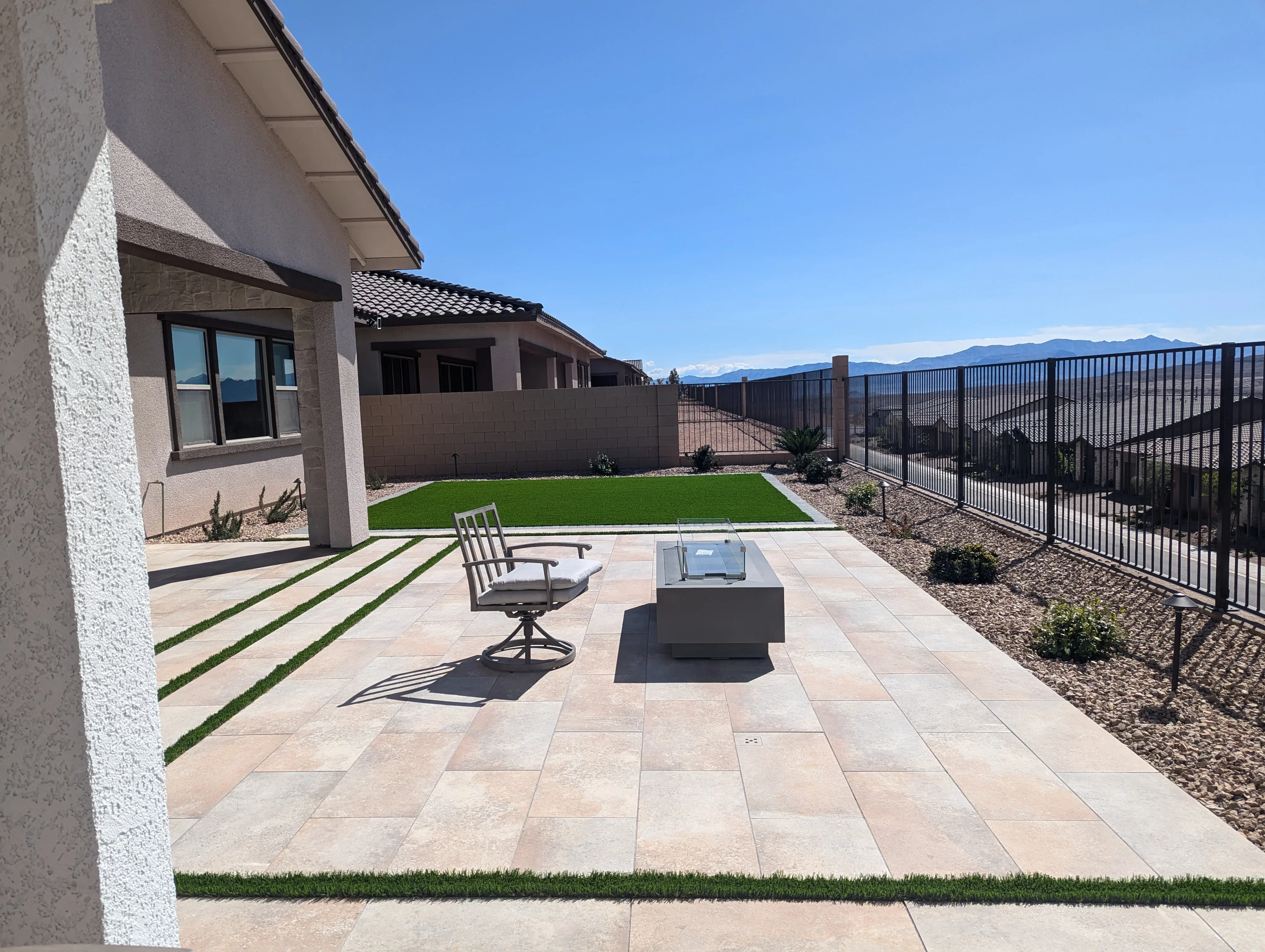 Modern patio with pavers, grass strips, fire pit, and mountain views in Las Vegas