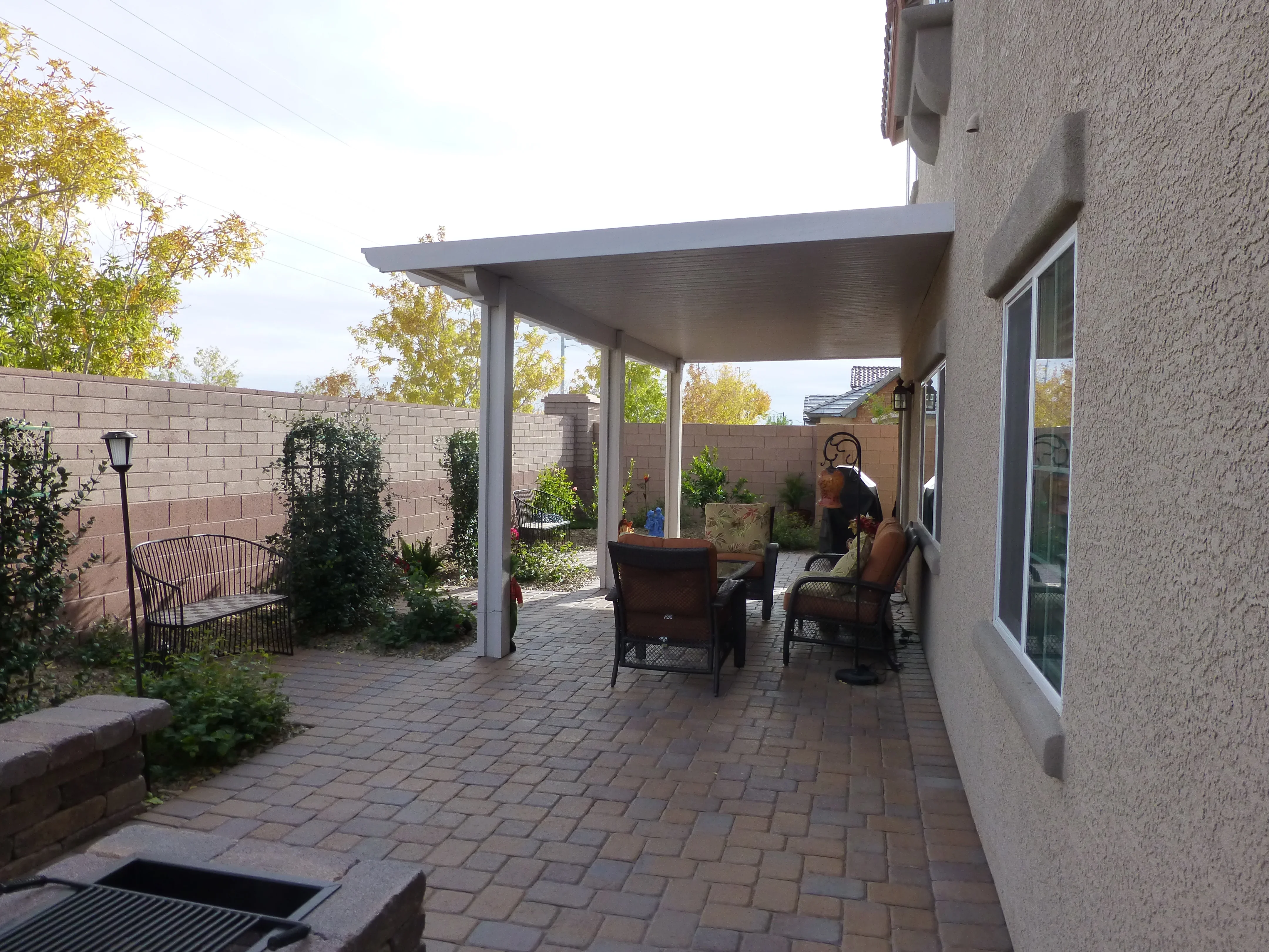 Modern patio cover with aluminum frame over brick pavers and outdoor seating area