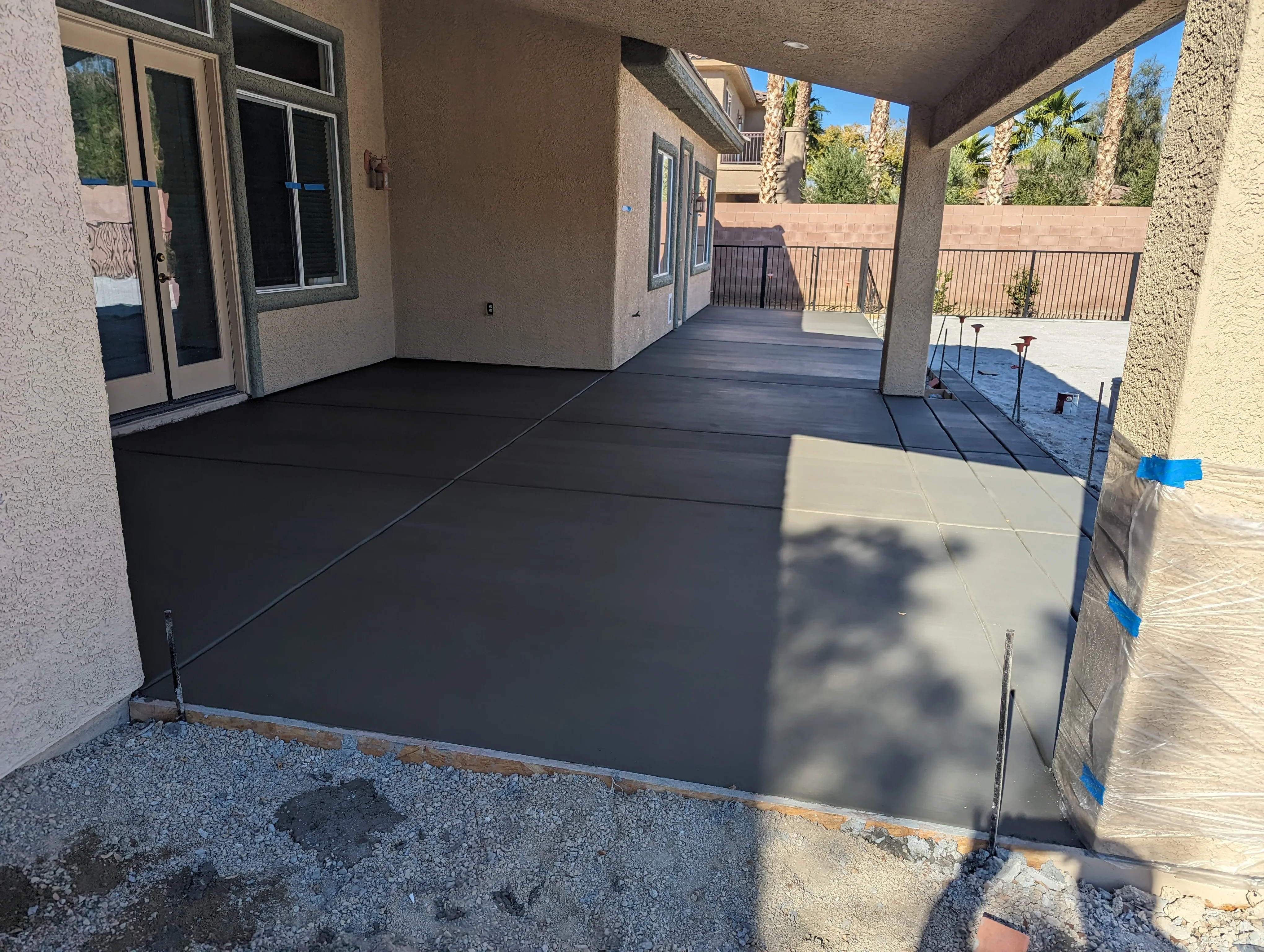 Dark concrete patio with pergola cover and metal railings overlooking desert landscape