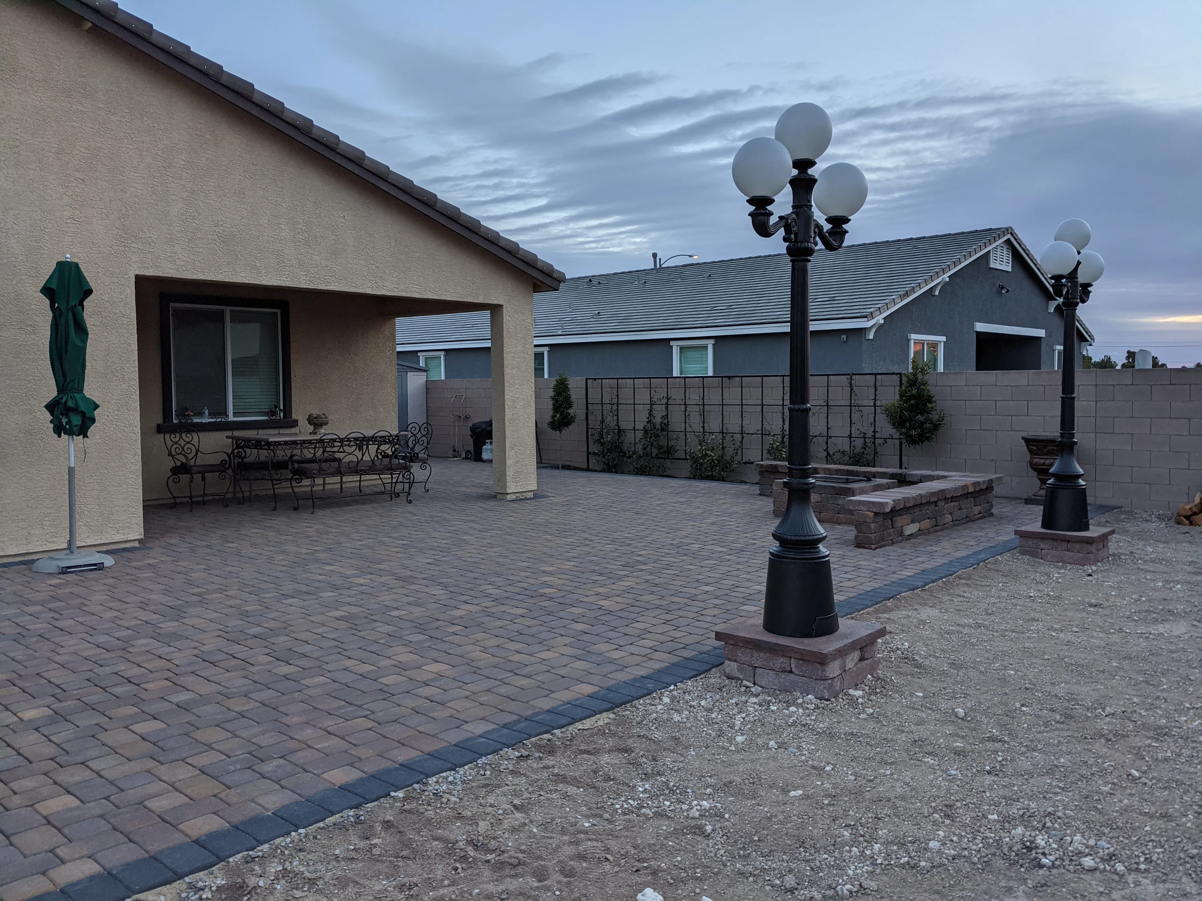 Large residential patio with permeable pavers, covered structure, and decorative street lamps