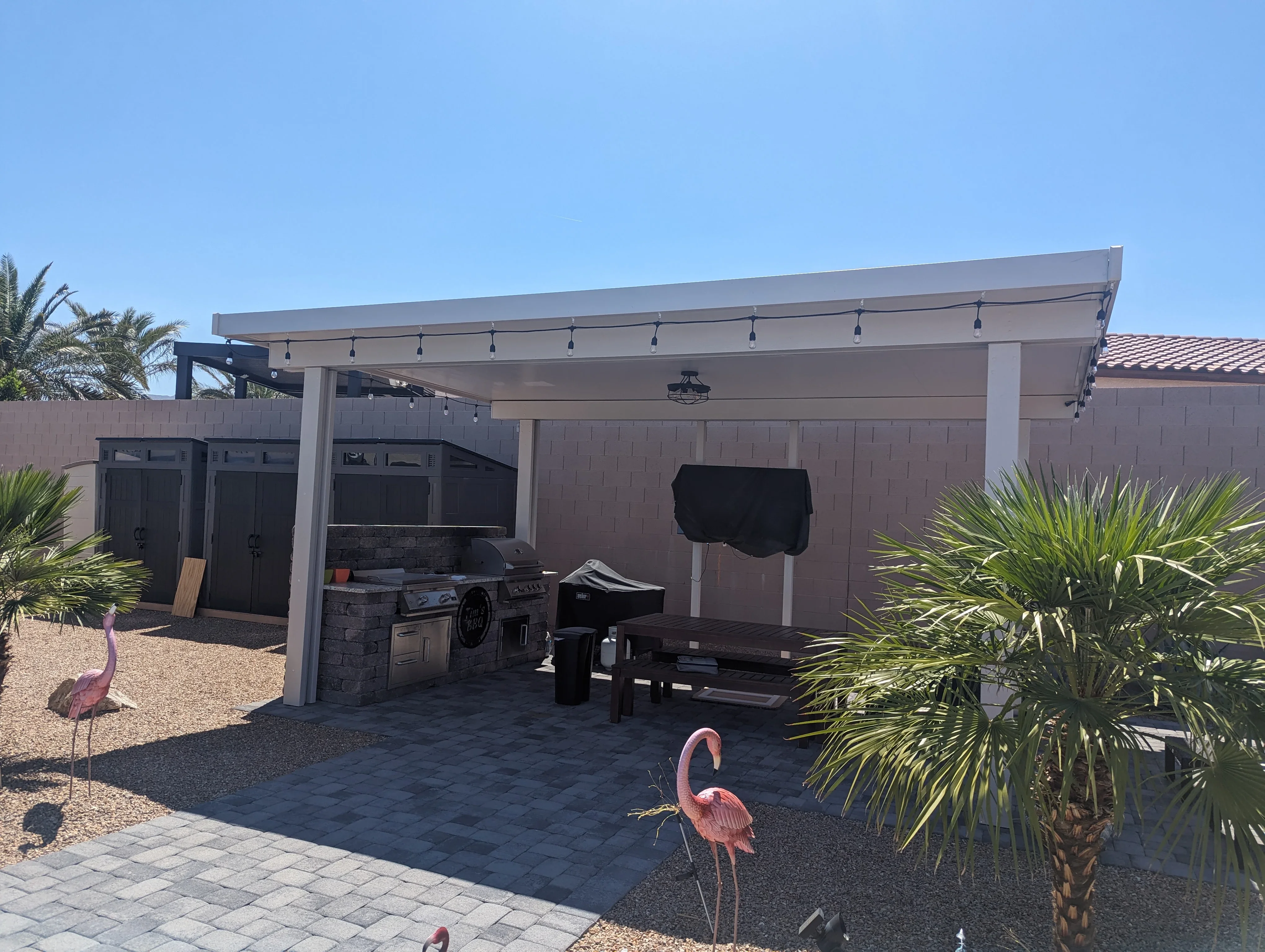 Modern pergola patio with motorized shade, outdoor kitchen, and desert landscaping in Las Vegas