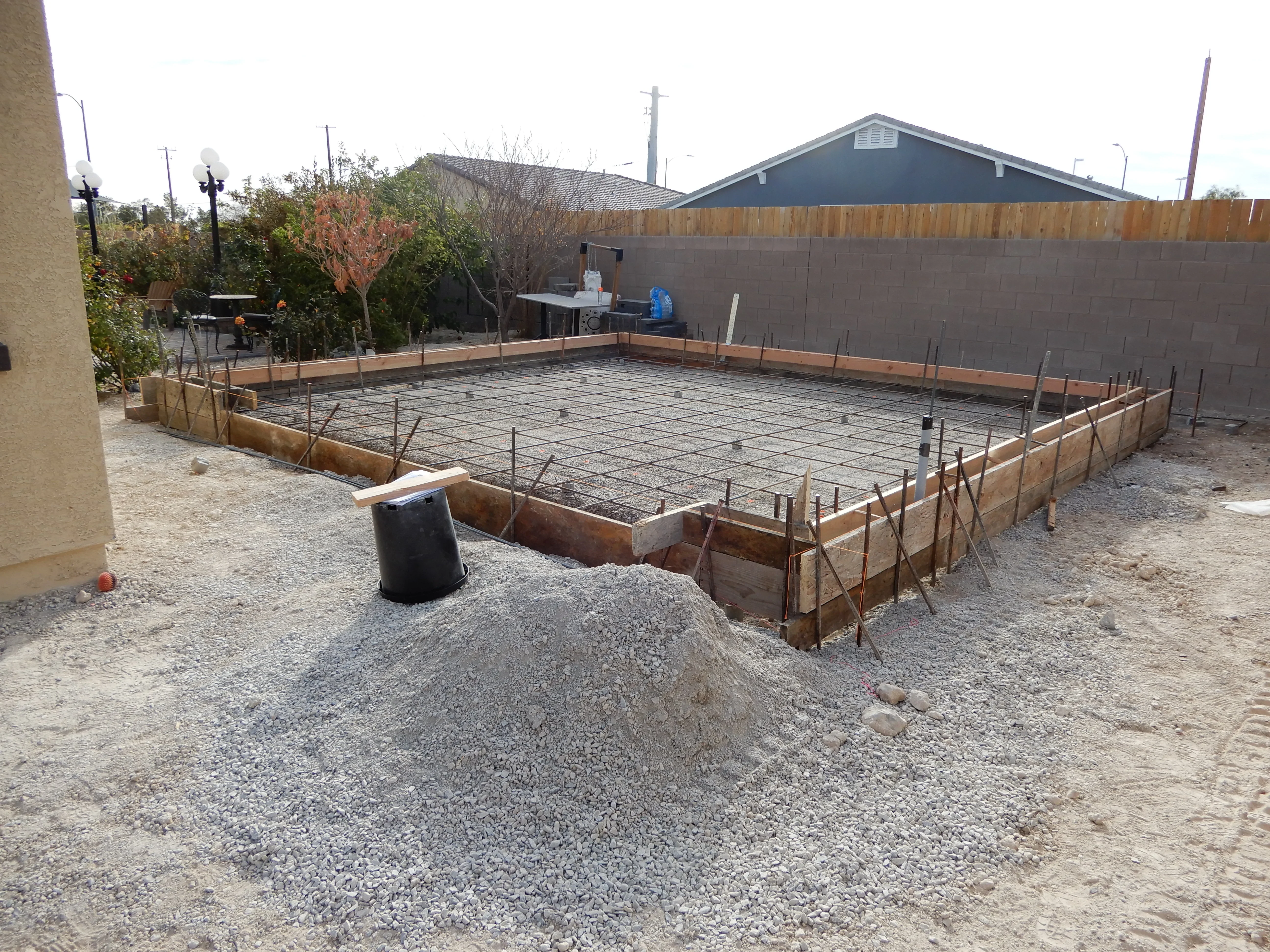 Concrete patio foundation with wooden forms, rebar grid, and gravel base ready for pour