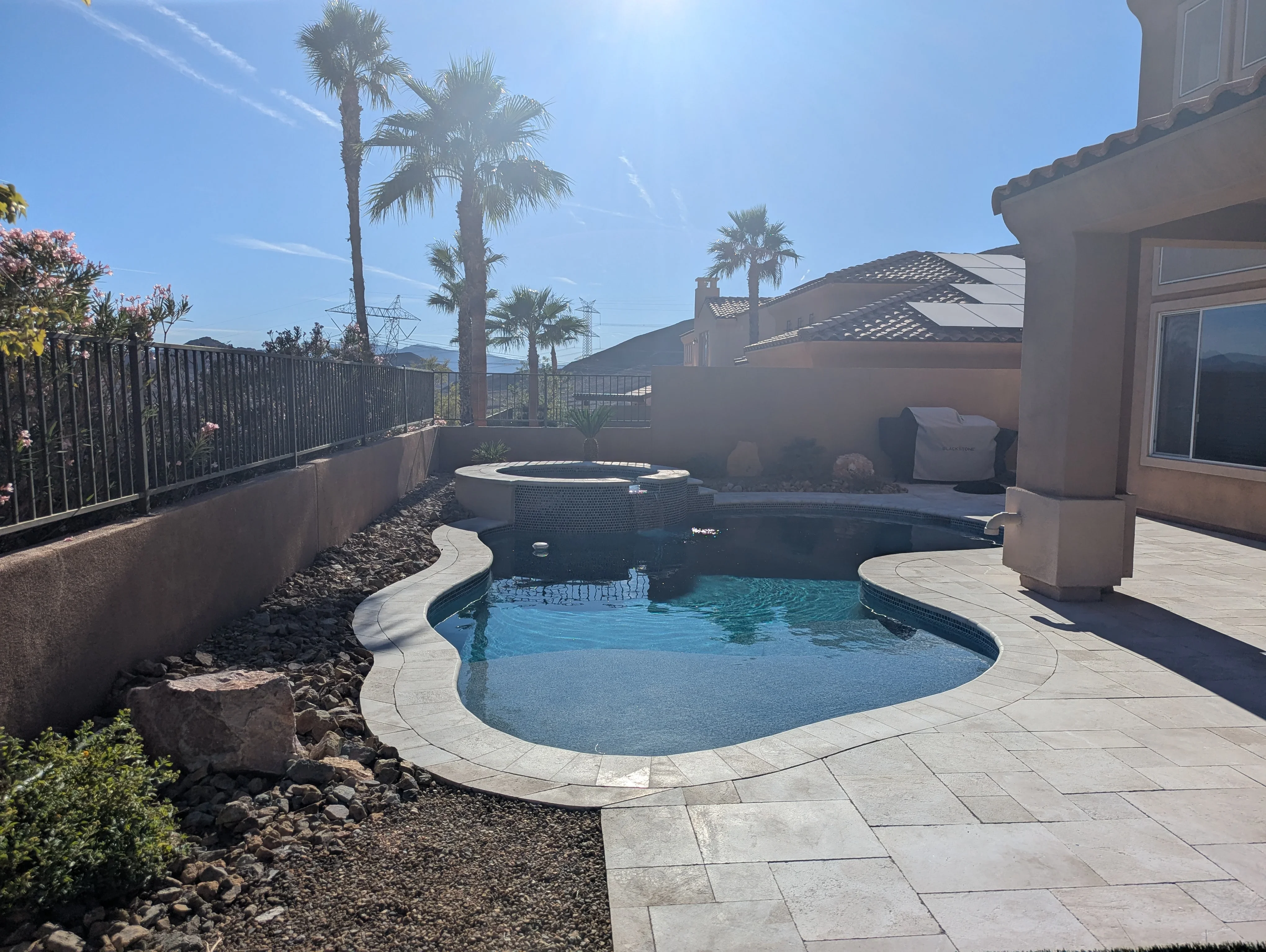 Luxury backyard pool and spa with stamped concrete patio, metal railings, and desert landscaping