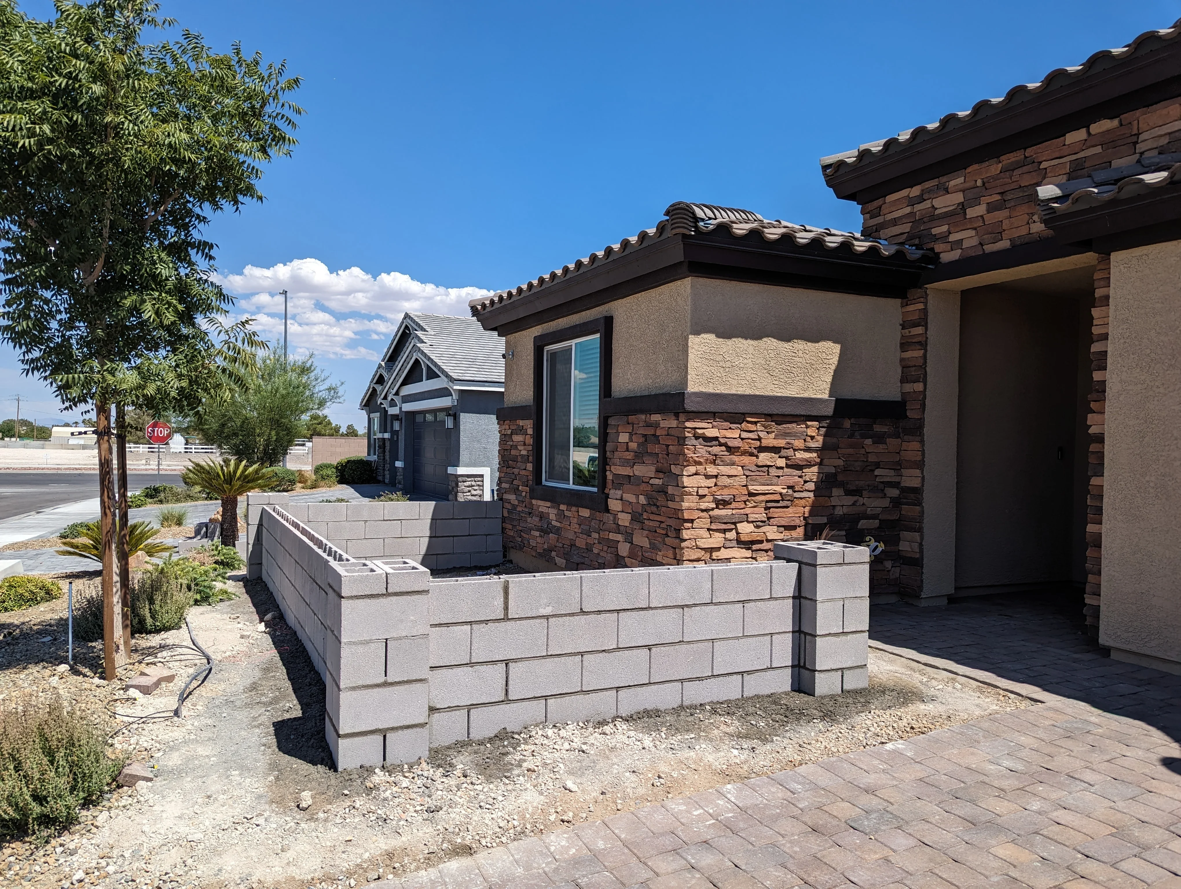 Gray concrete block retaining wall with metal railings and paver pathway in front of modern home