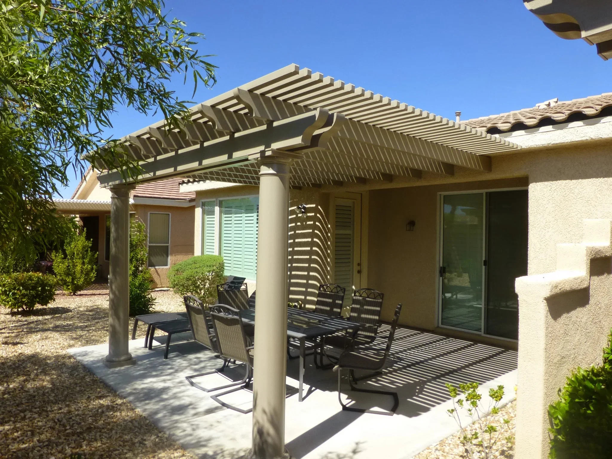 Modern pergola with horizontal slats over concrete patio and outdoor seating furniture