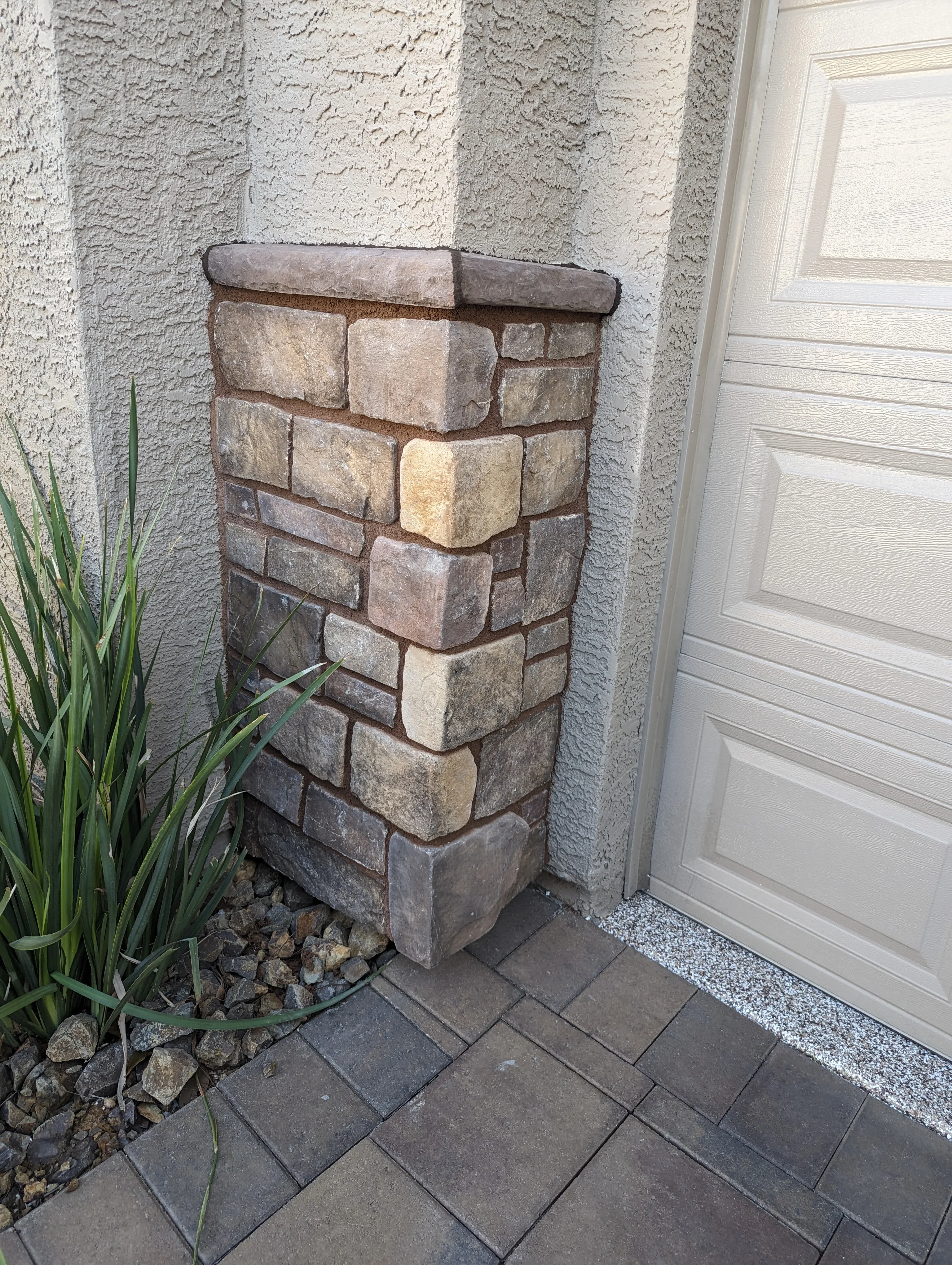 Stacked stone veneer pillar with earth-tone blocks and finished cap at home entrance