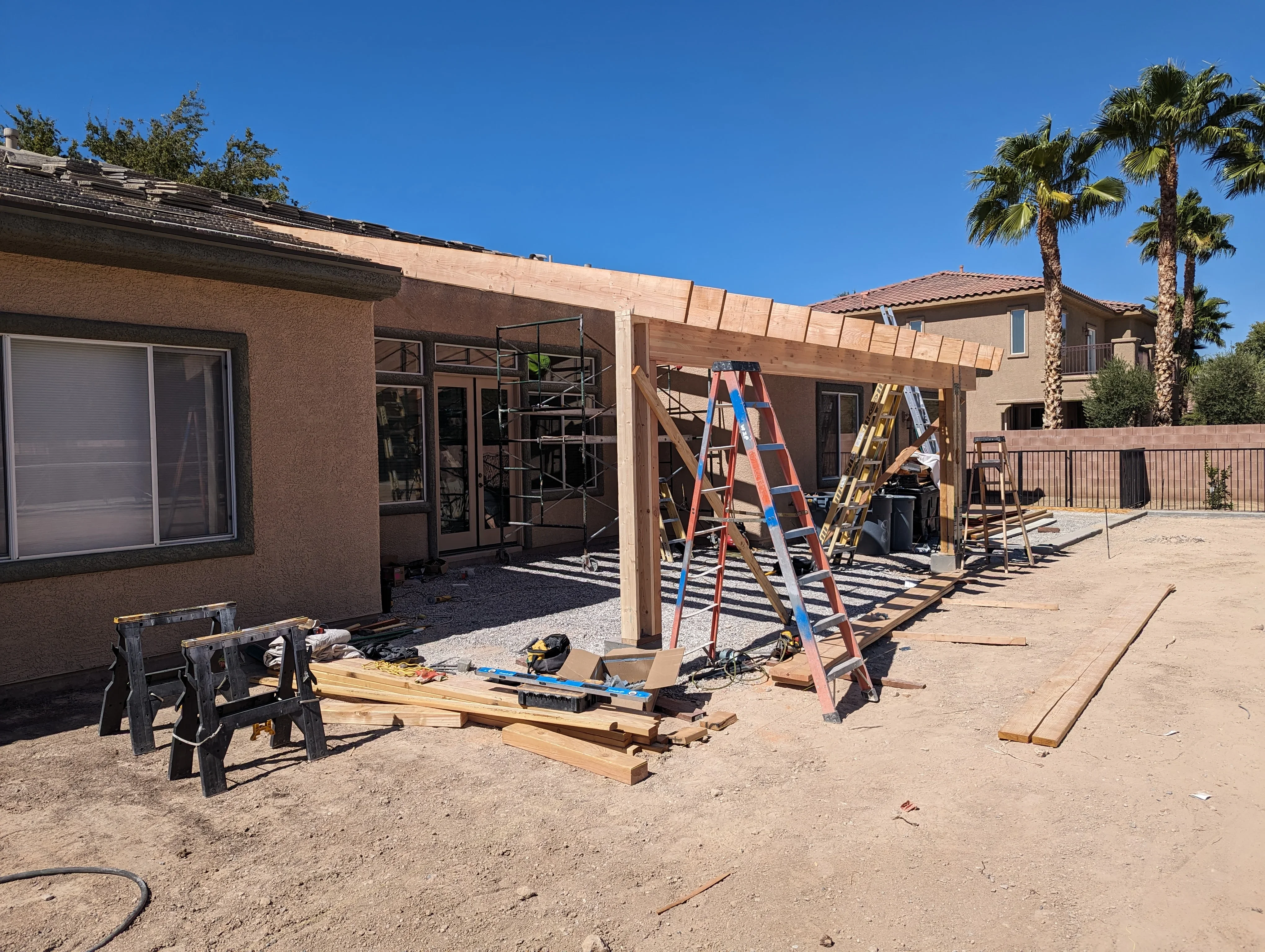 Residential patio under construction with wooden pergola framing and support posts