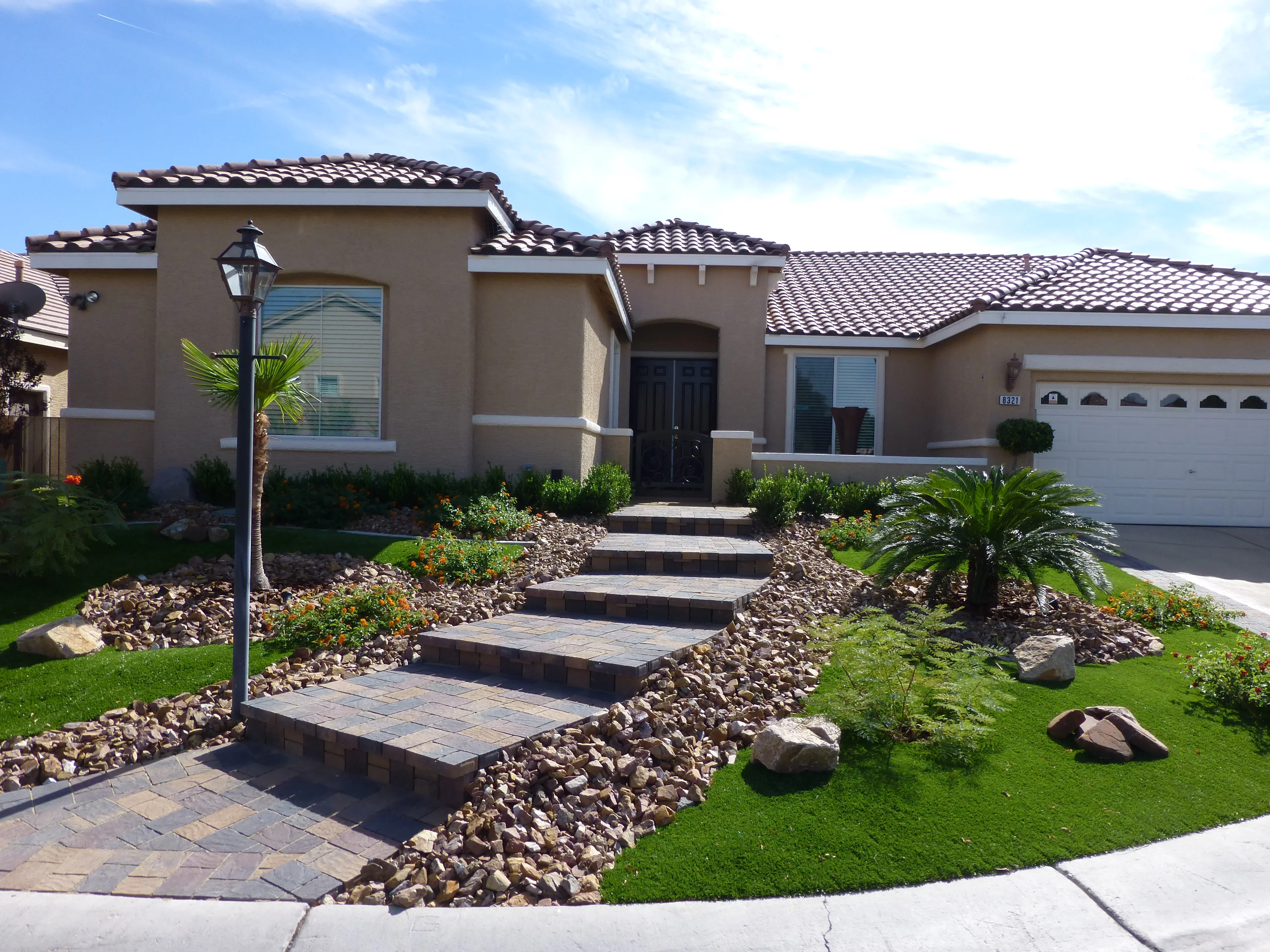 Front yard hardscape with paver walkway, river rock landscaping, and tropical plants