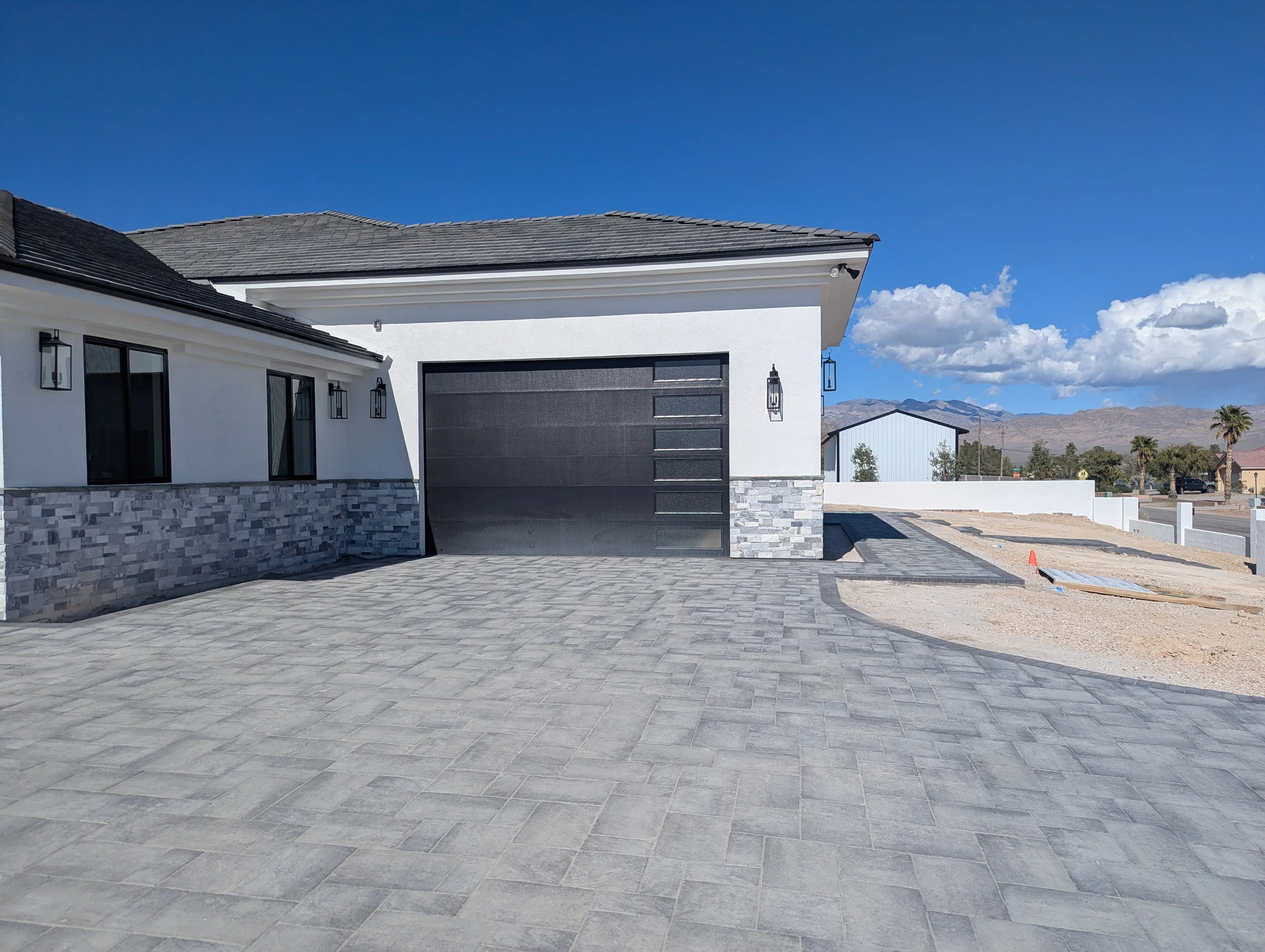 Modern home with gray herringbone patterned concrete driveway and stone veneer accents