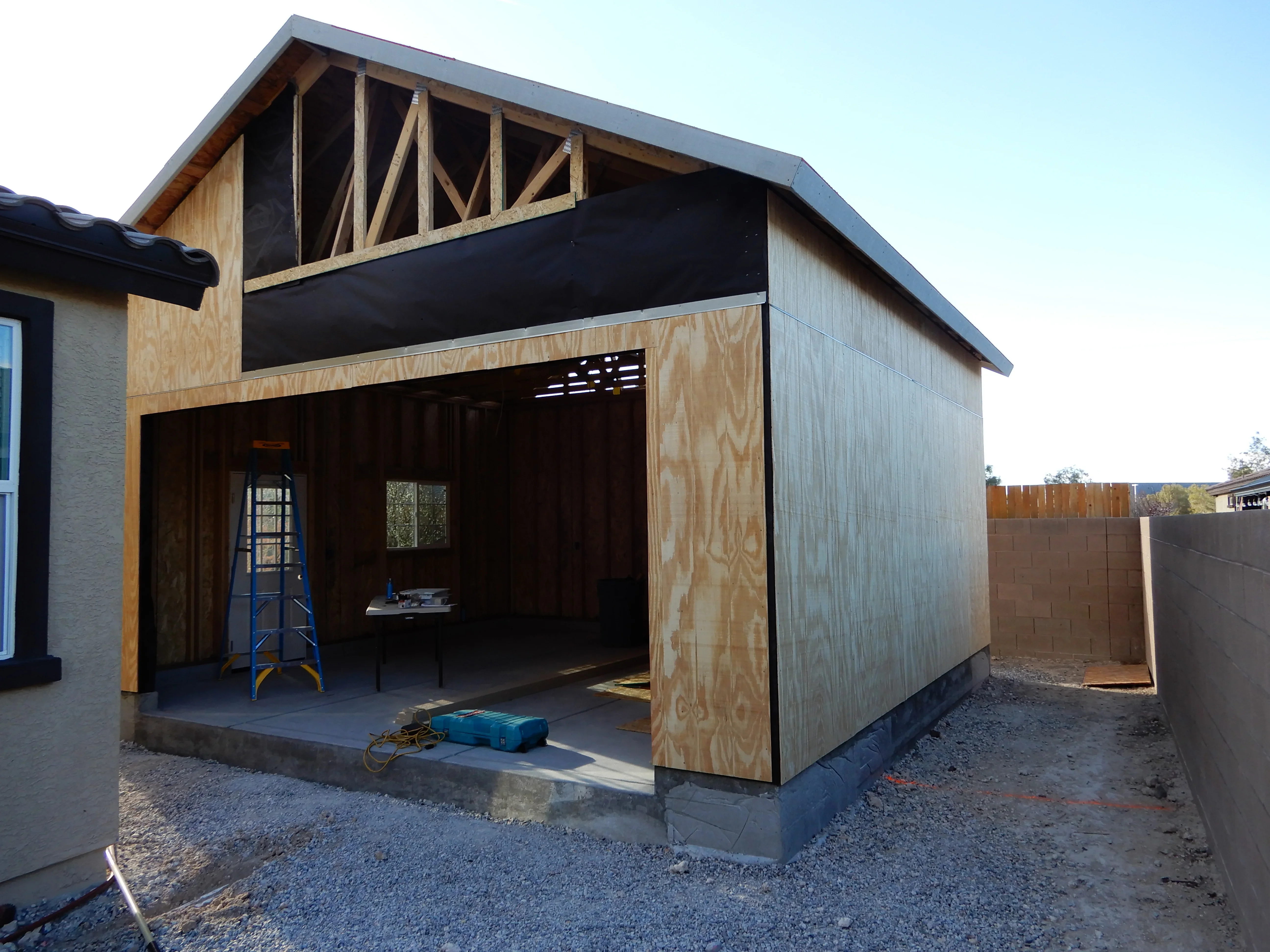 Modern covered patio with exposed beams, plywood walls, and metal roof under construction