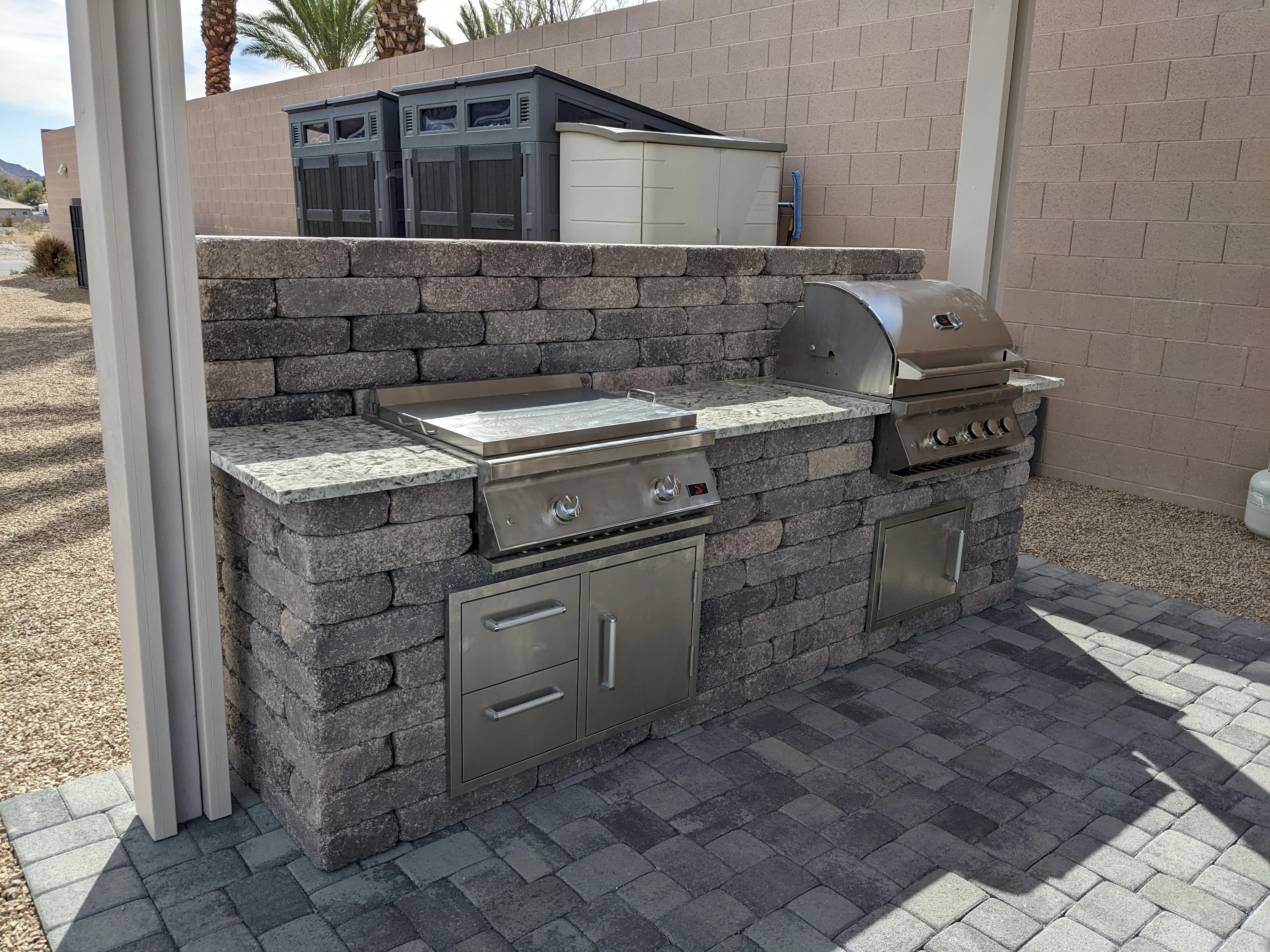 Outdoor kitchen with gray stacked stone base, granite counters, and stainless steel appliances