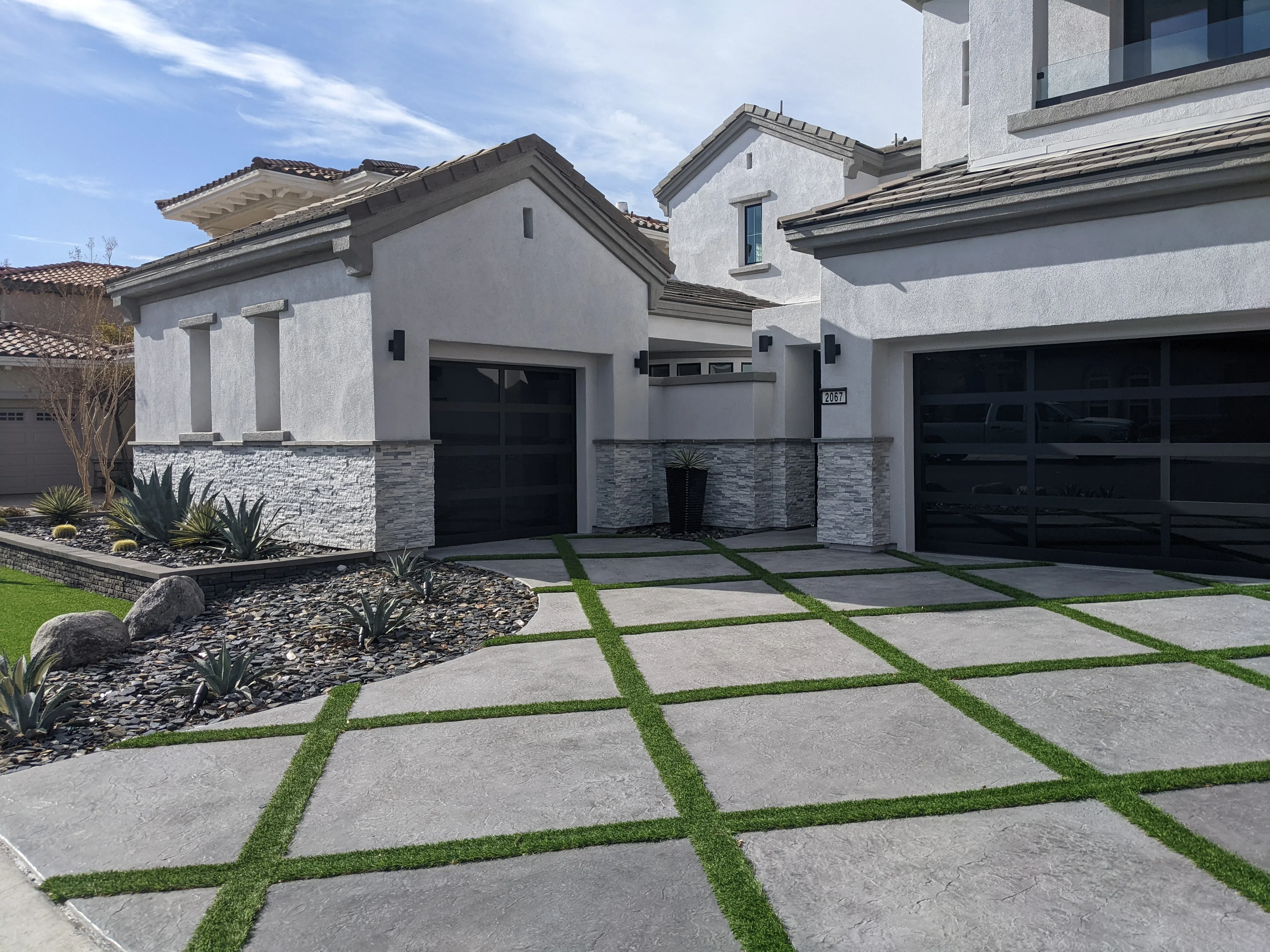 Modern driveway with concrete pavers and grass strips, desert landscaping, contemporary home