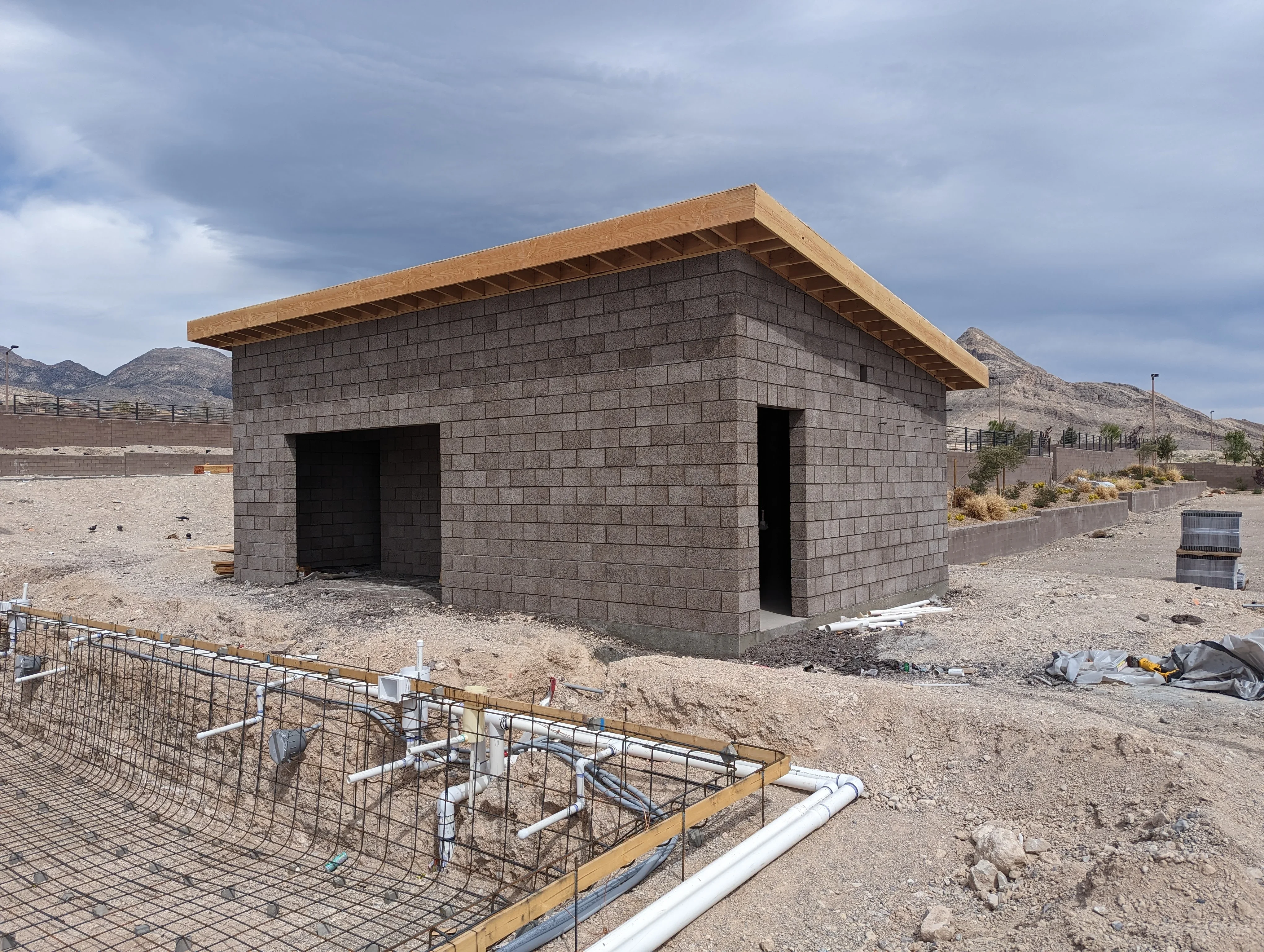 Concrete block building with wood roof beams under construction in desert setting