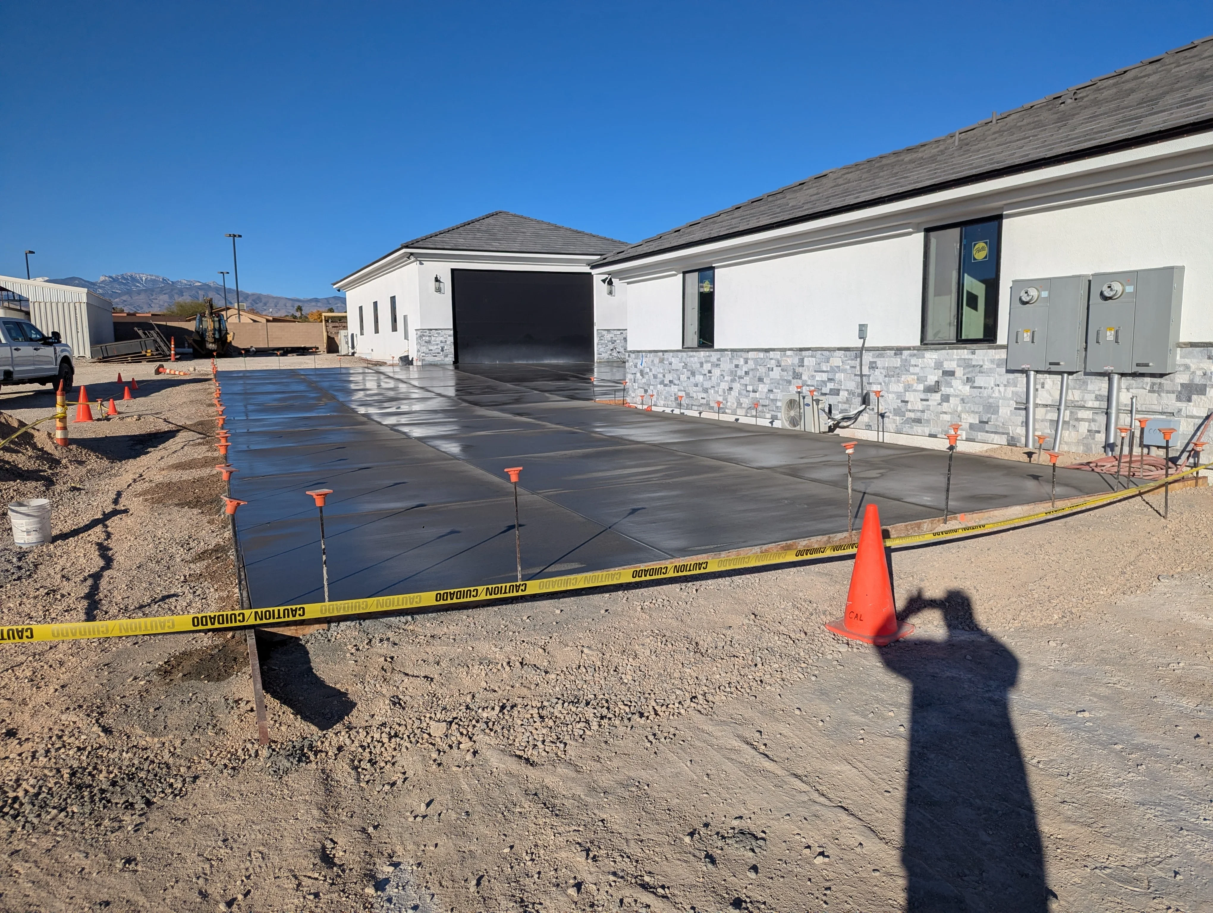 New concrete driveway and patio with stone veneer accents on modern home