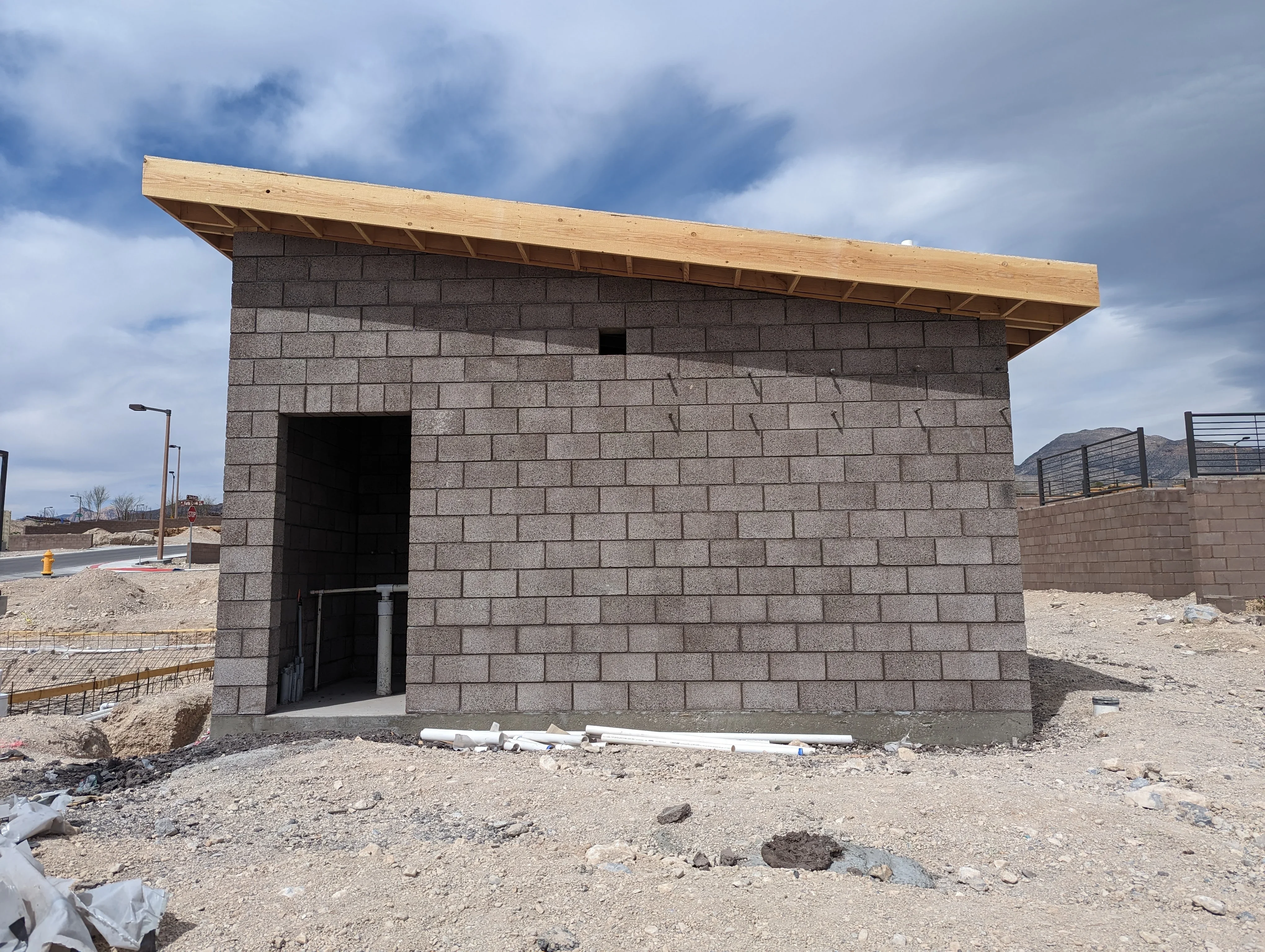 Gray concrete block building with wood beam overhang and recessed entry door