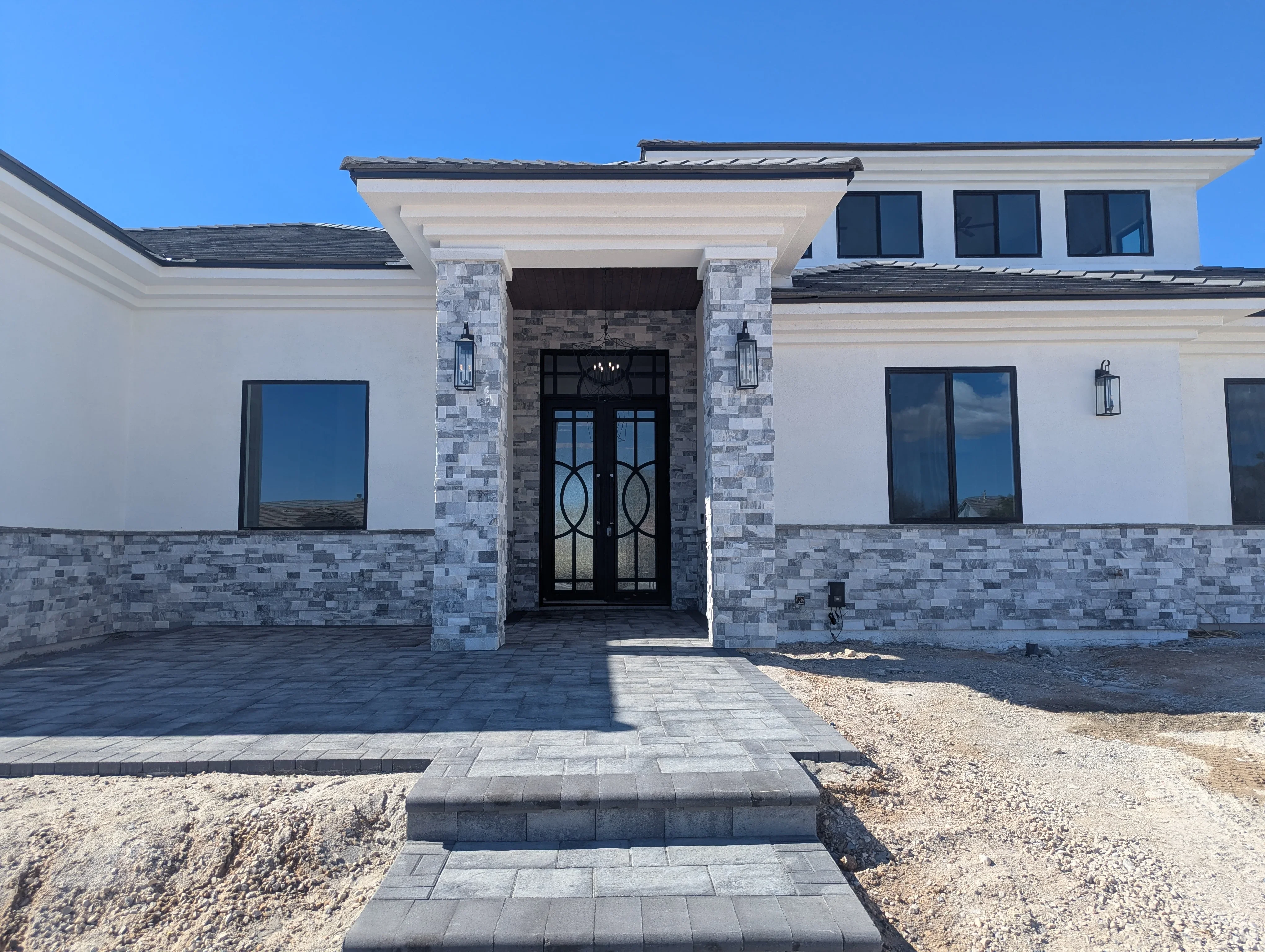 Modern home entry with gray paver patio and stacked stone veneer columns