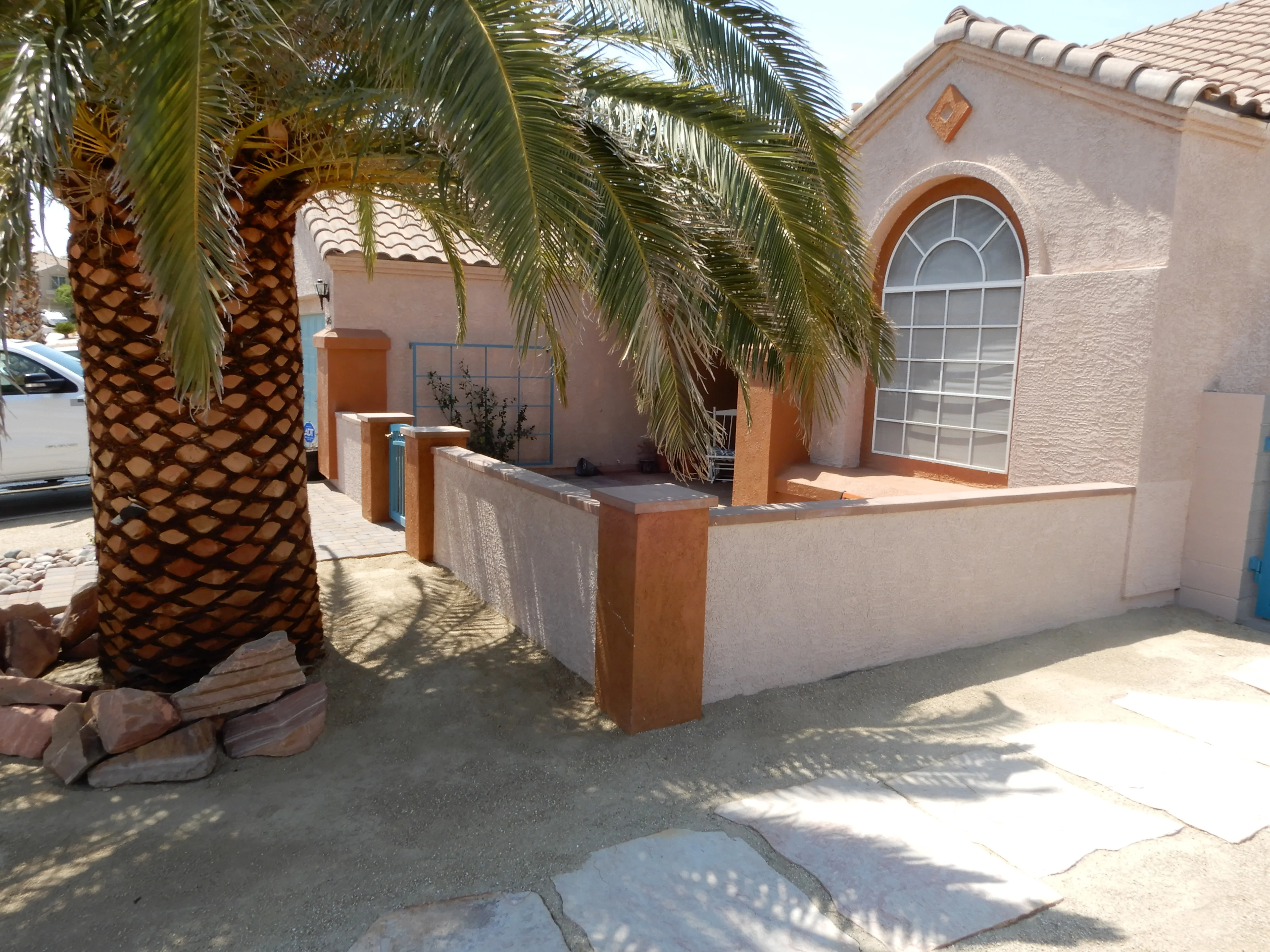 Stucco courtyard with concrete hardscape, planter boxes, and palm trees