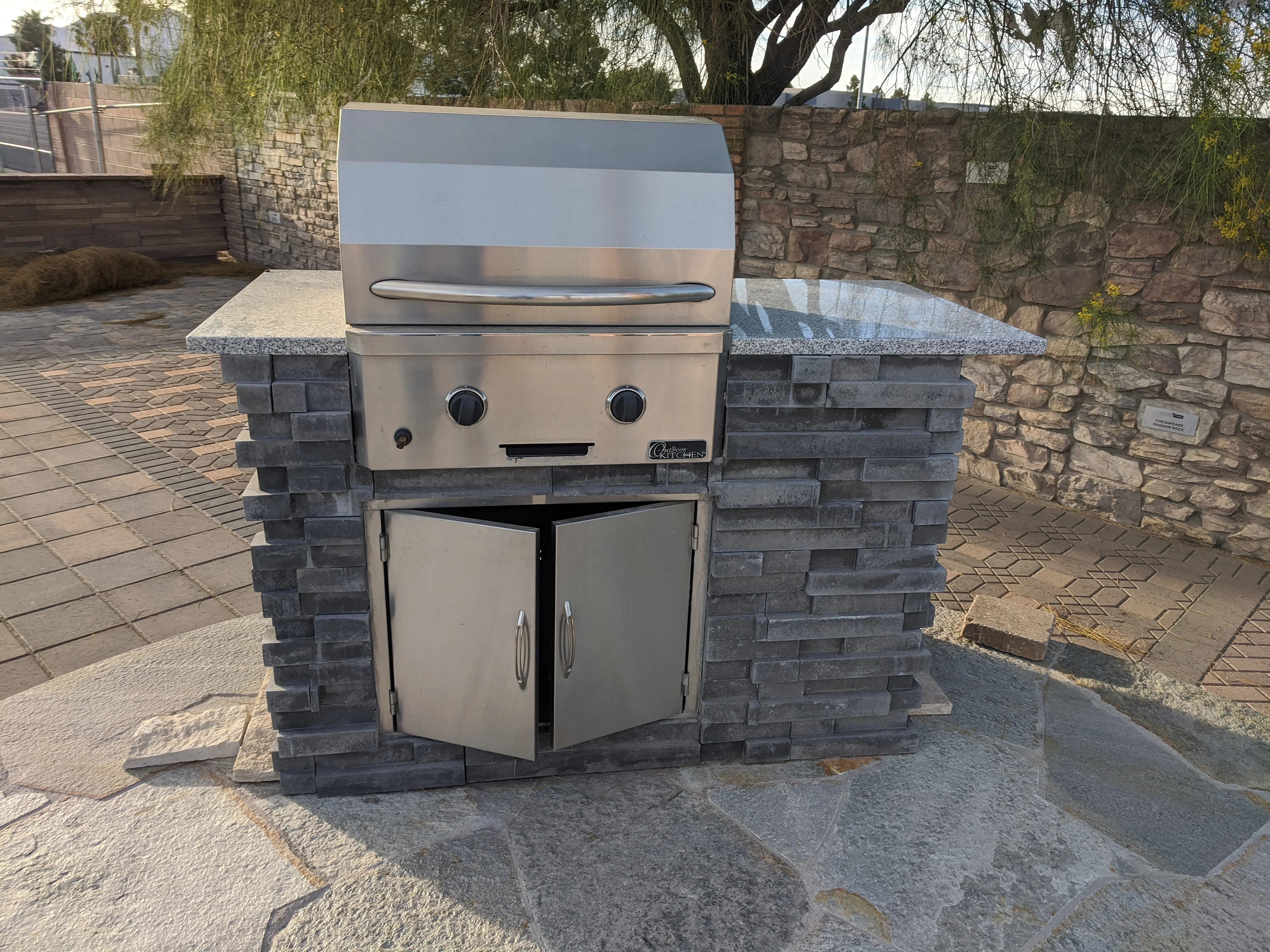 Stainless steel grill in stone veneer island with granite counters and storage cabinets