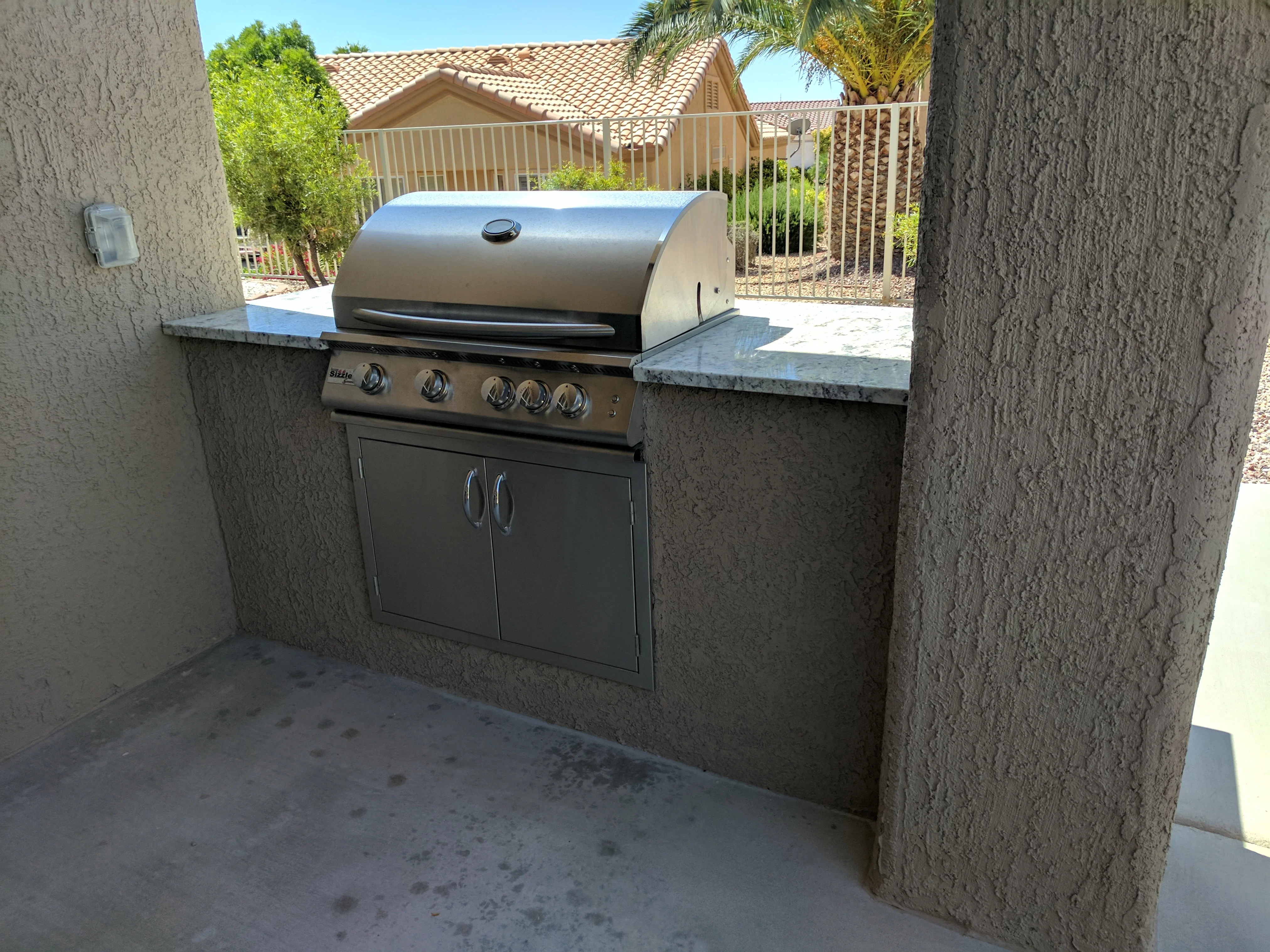 Built-in stainless steel grill island with concrete walls and granite countertops in Las Vegas patio