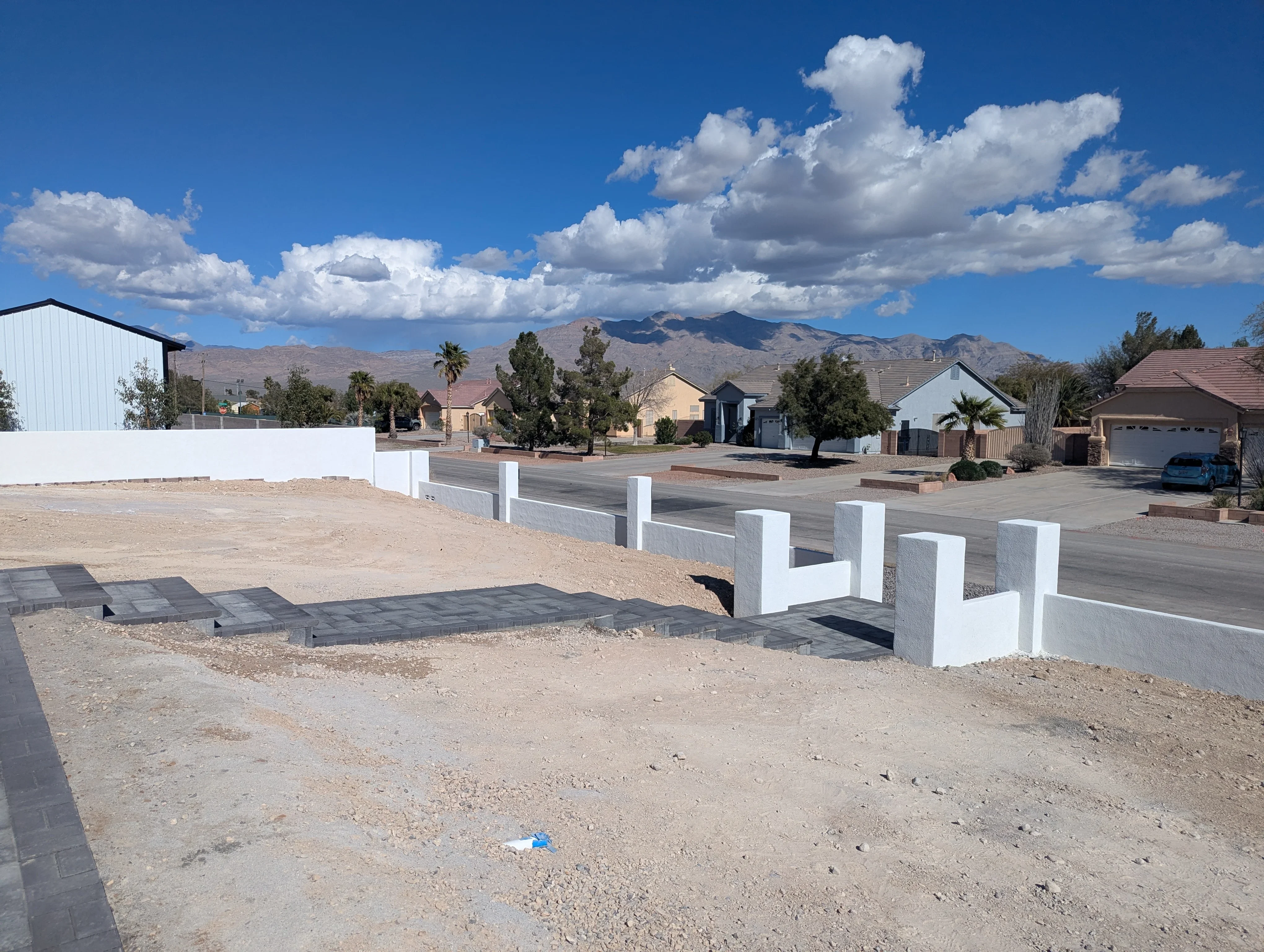White concrete retaining wall blocks installed along new driveway with desert mountains in background
