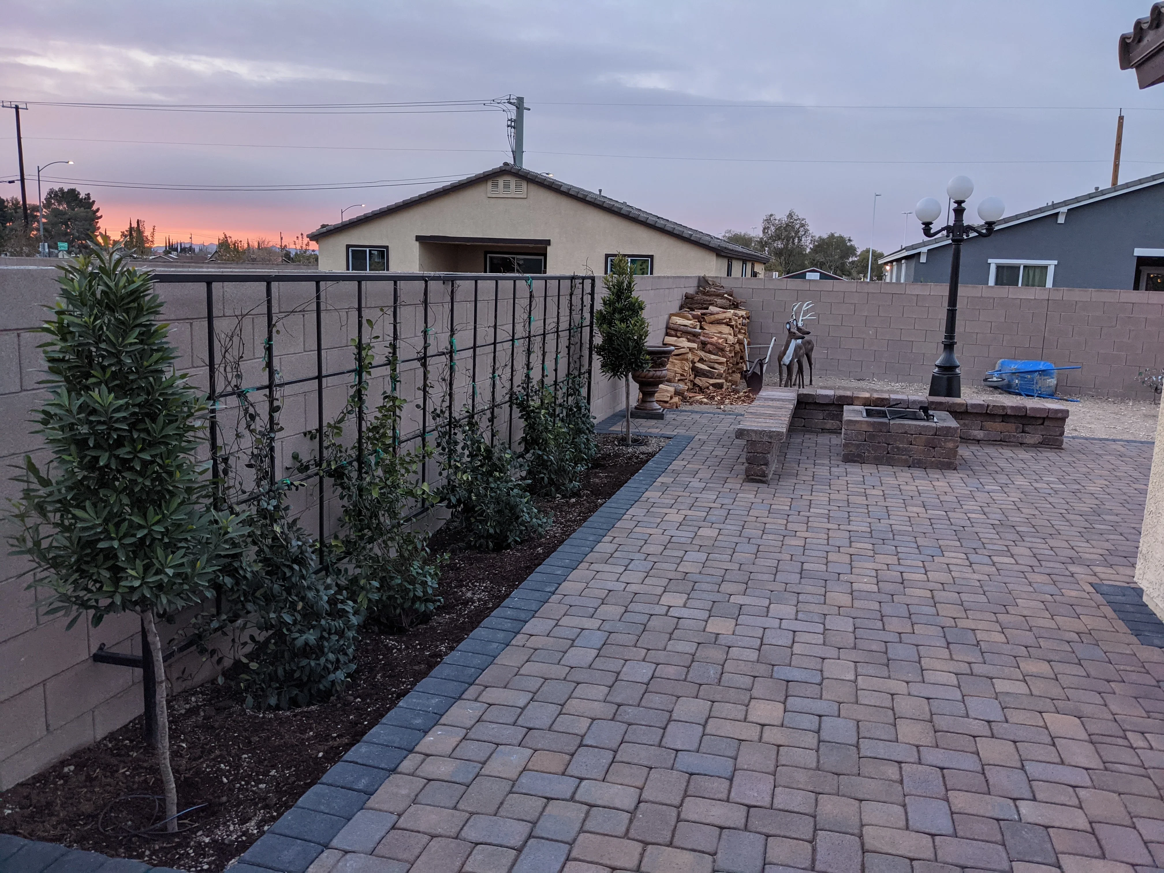 Modern patio with permeable pavers, concrete walls, and landscaped planting beds at dusk