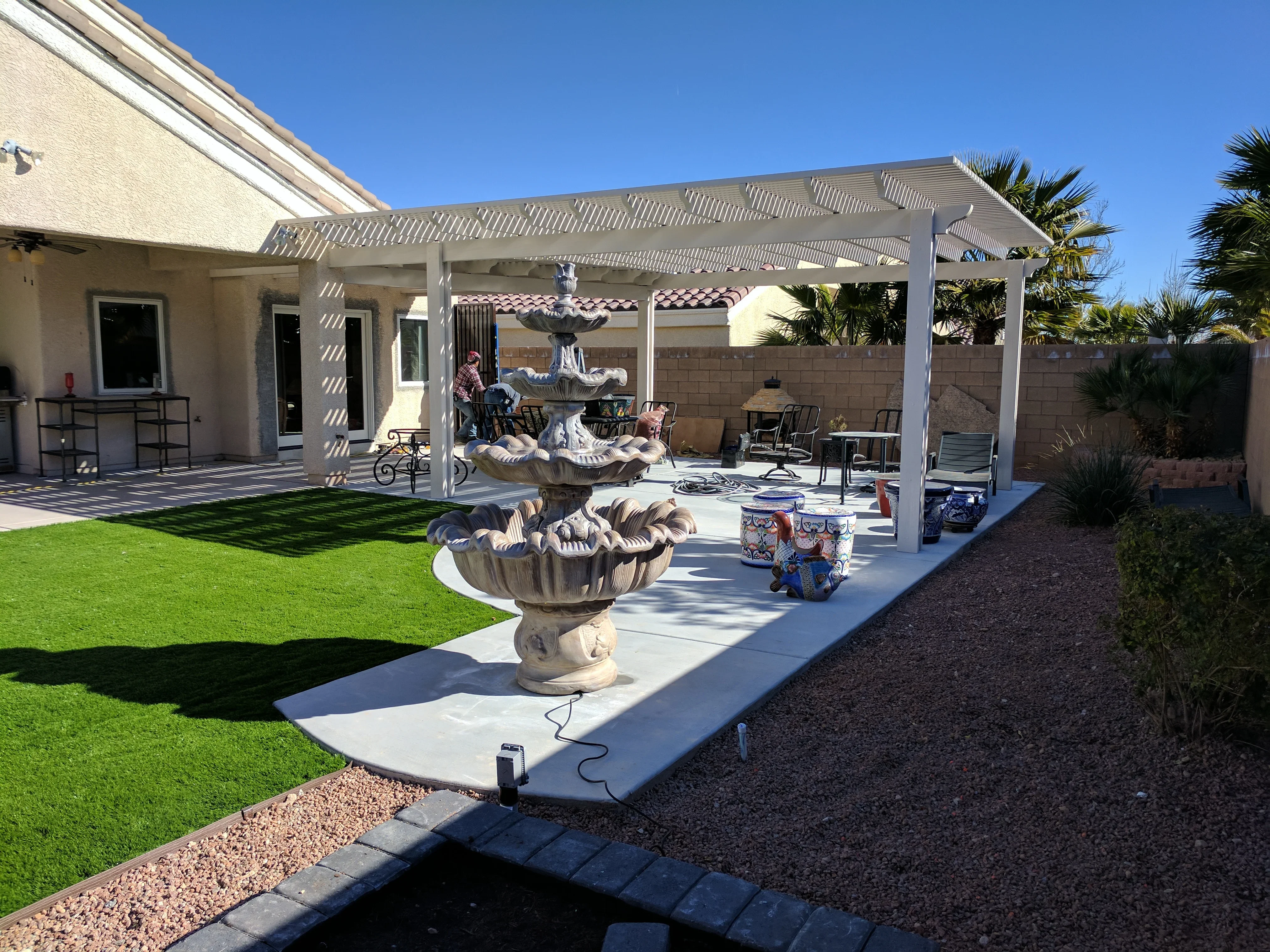 Modern white pergola patio with synthetic turf, concrete decking, and privacy wall in Las Vegas