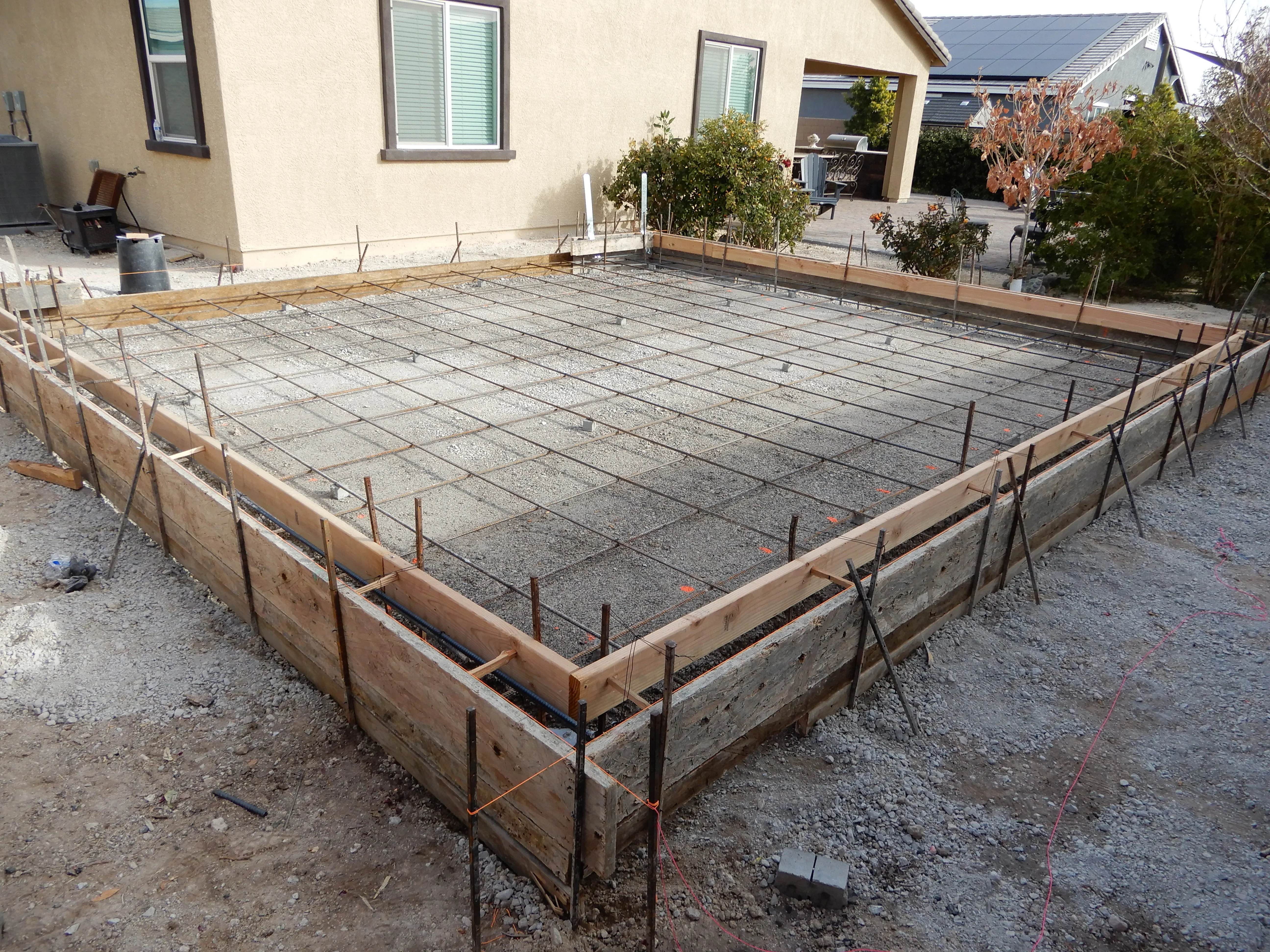 Concrete patio foundation with rebar grid and wooden forms in Las Vegas backyard