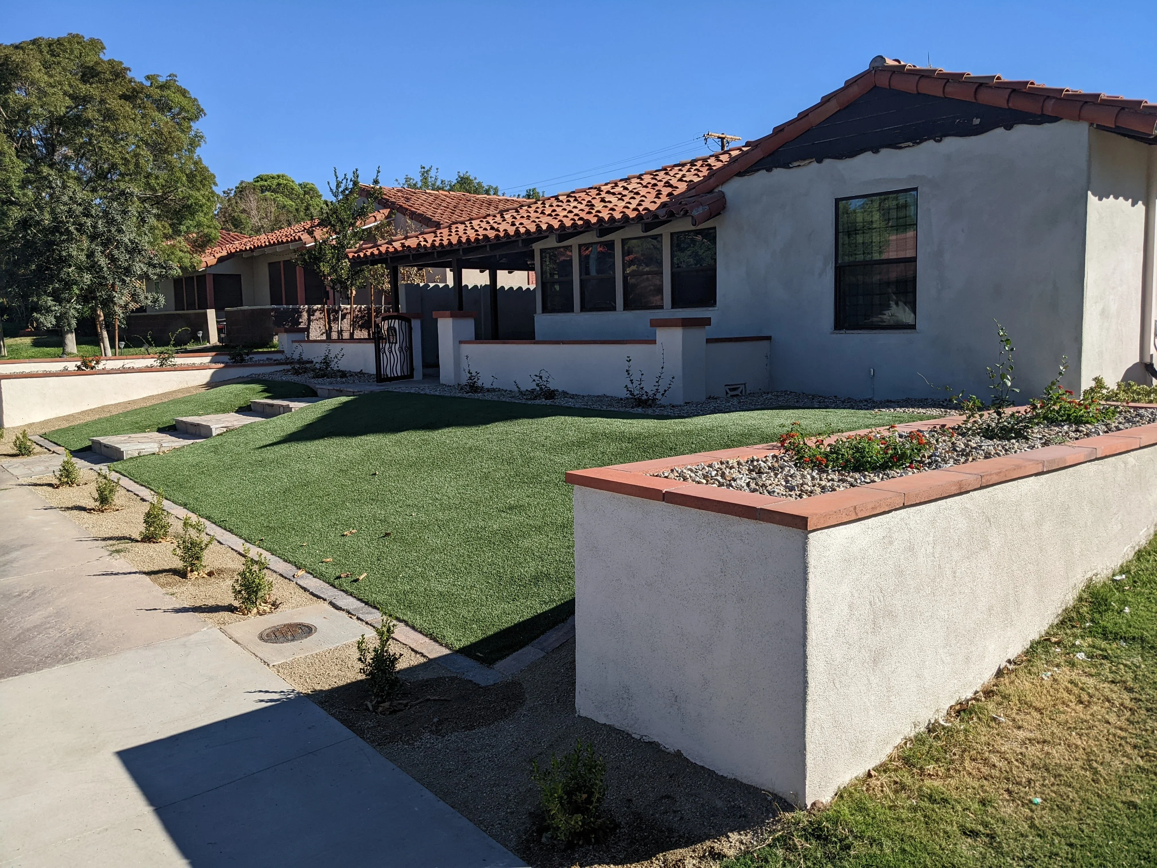 Spanish Colonial home with new lawn, raised planters, and landscape beds
