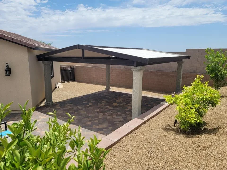 Black steel patio cover with concrete columns over dark pavers in Las Vegas backyard