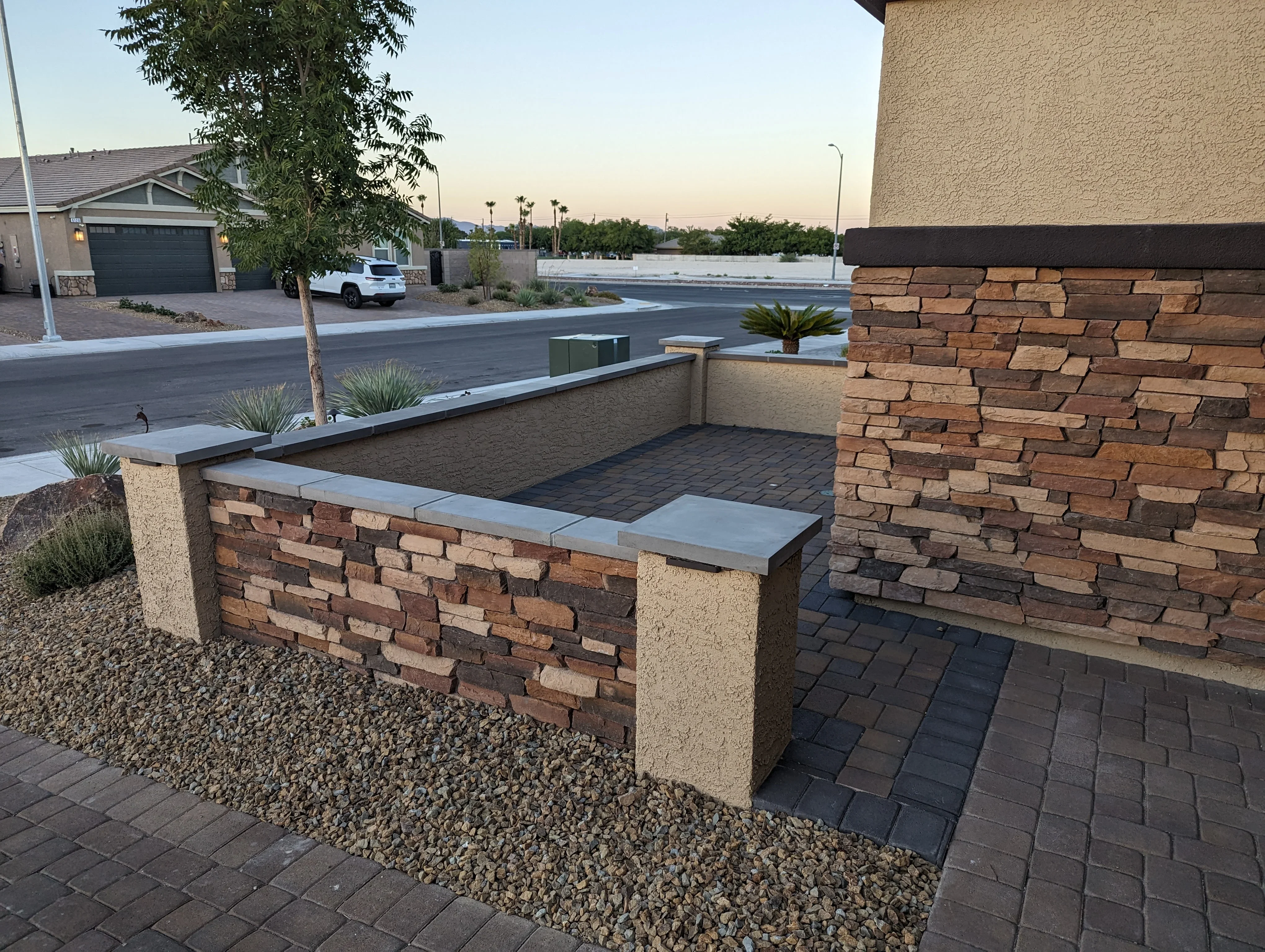 Custom brick seating wall with stone cap on dark paver patio in Las Vegas residential setting