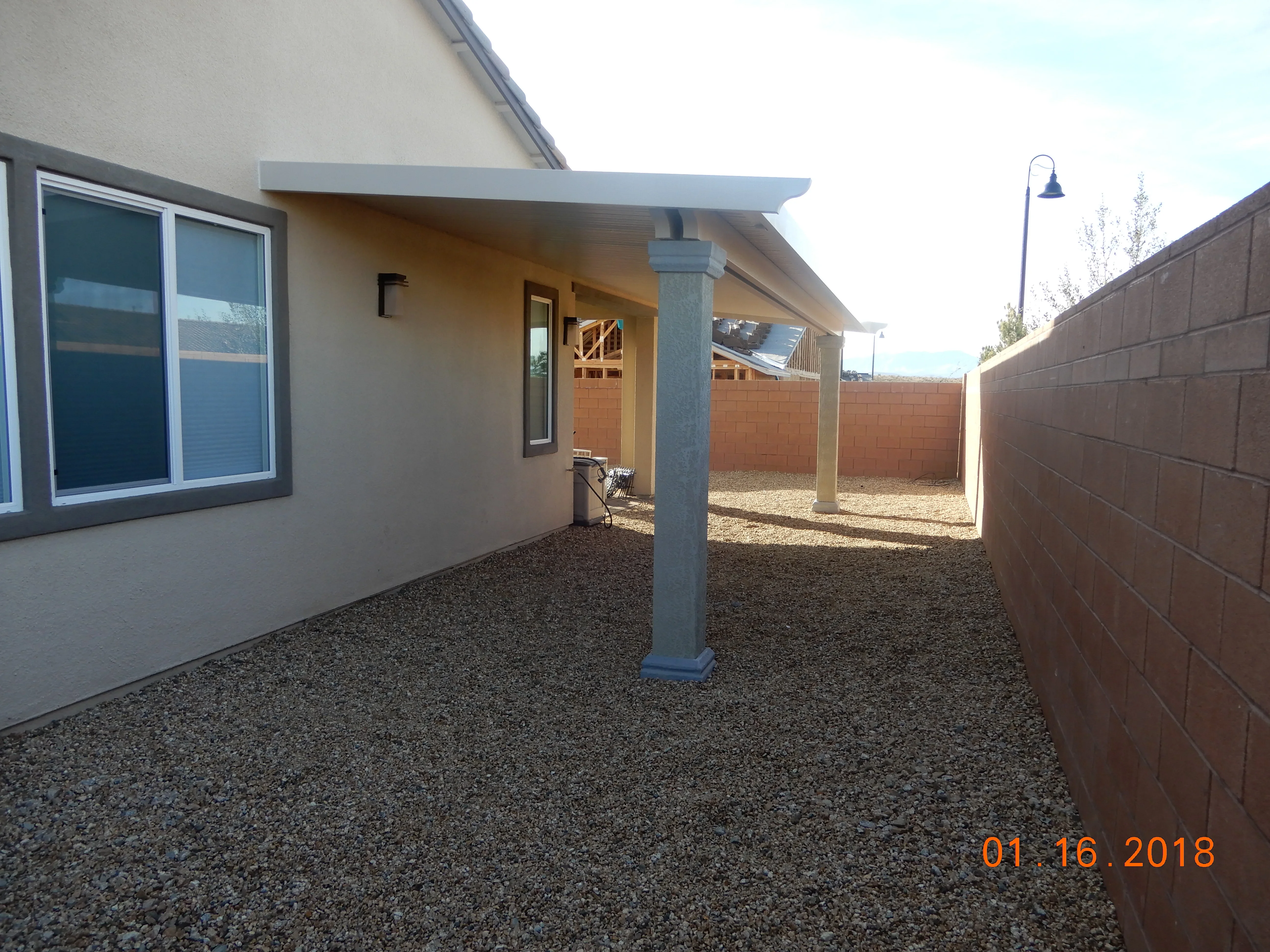Modern covered patio with pergola, steel columns, and gravel surface in Las Vegas backyard