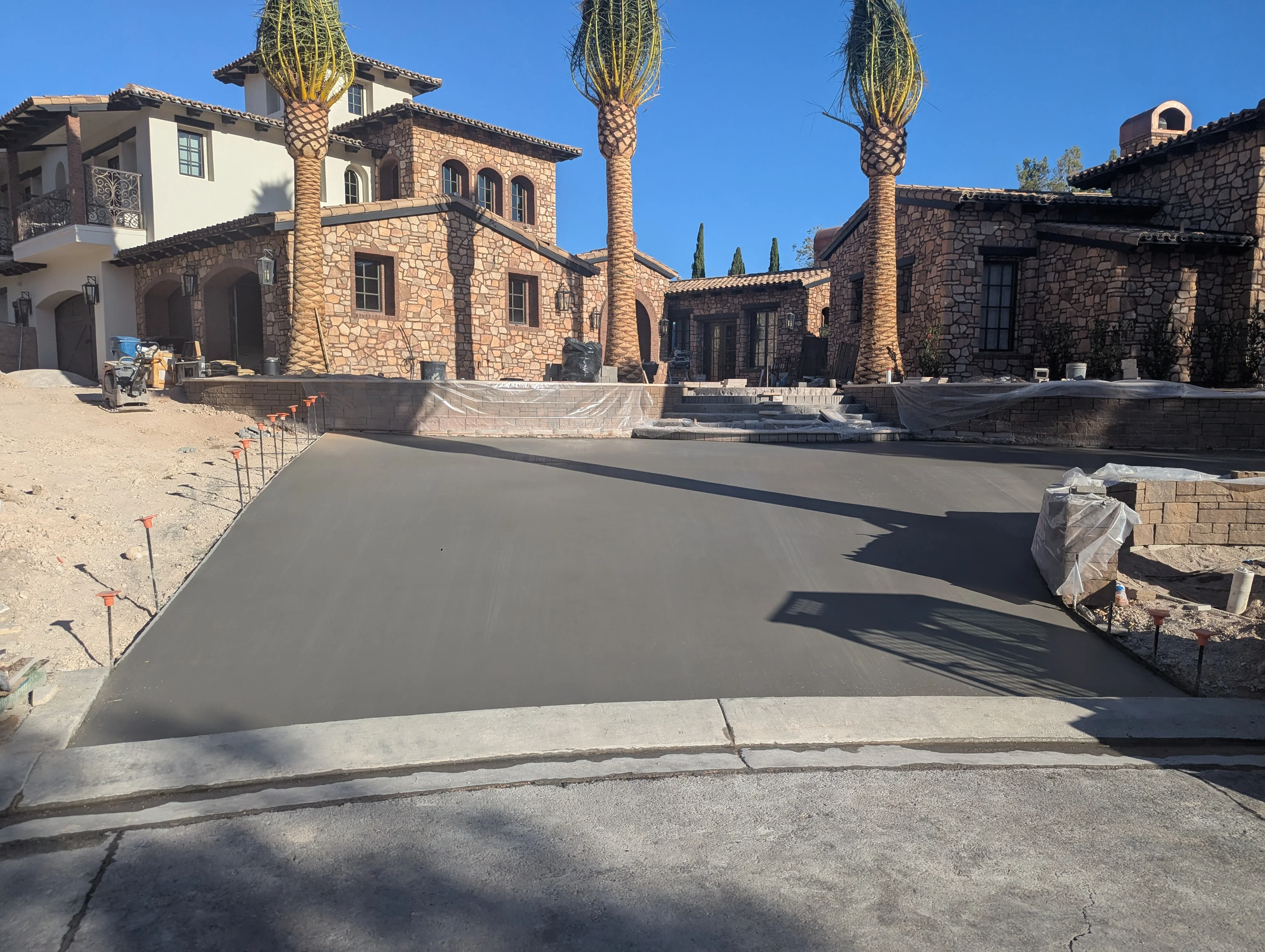 Finished concrete courtyard with control joints in front of Mediterranean stone buildings and palm trees