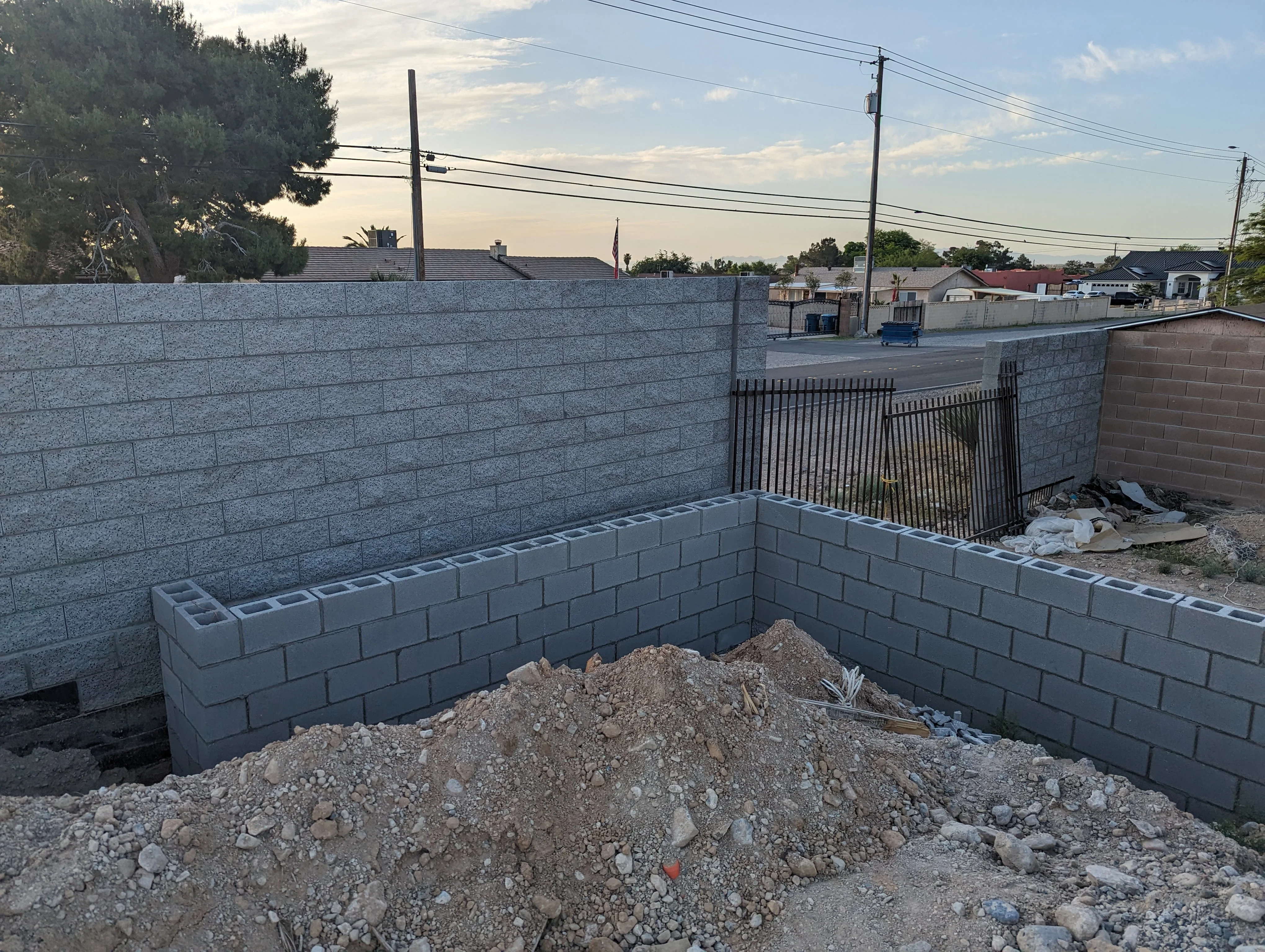 Multi-tiered concrete block retaining wall under construction with gray blocks and metal railing