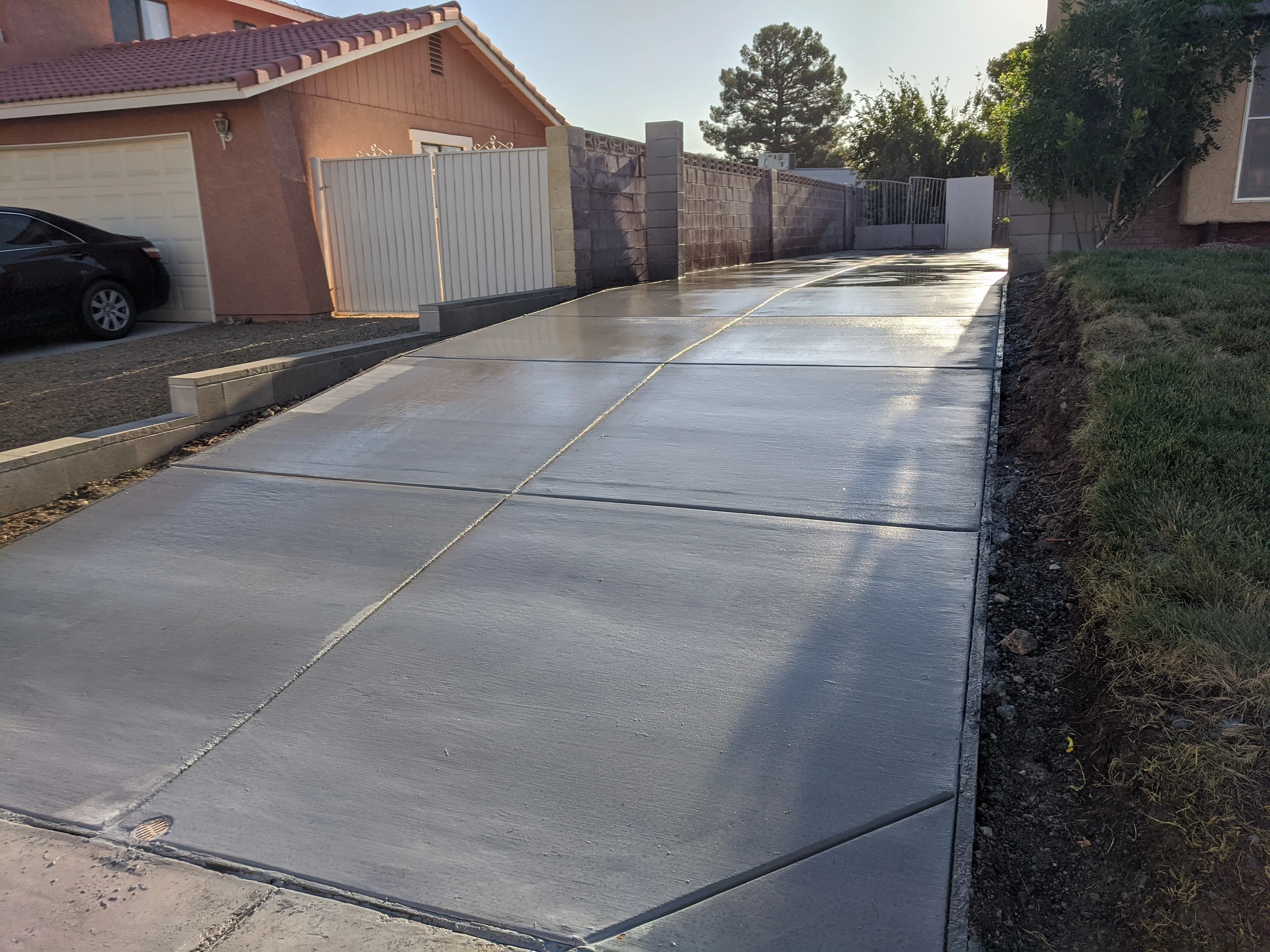 Newly poured concrete driveway with control joints and finished surface in residential setting
