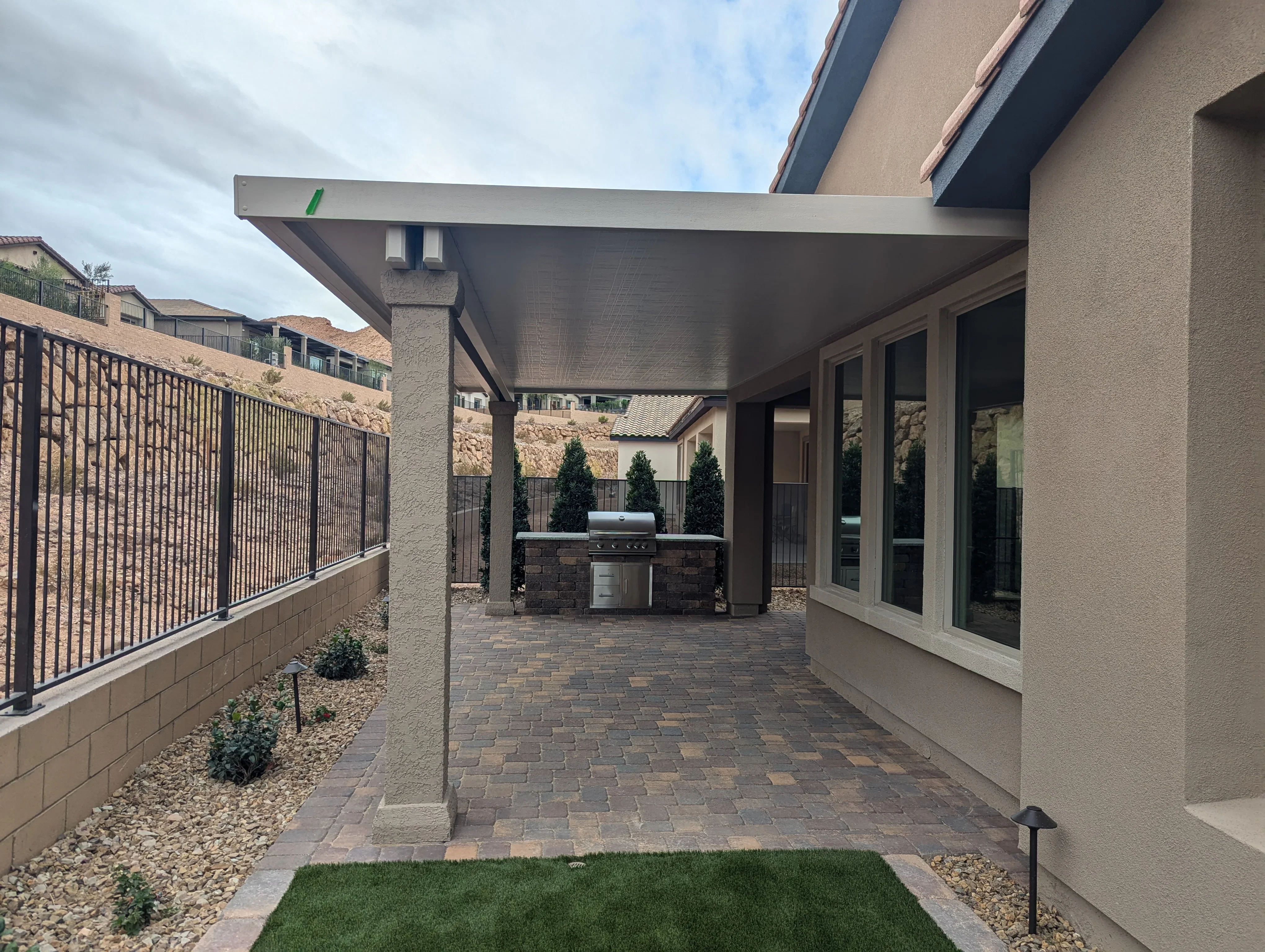 Modern covered patio with pergola, outdoor kitchen, and paver flooring in Las Vegas