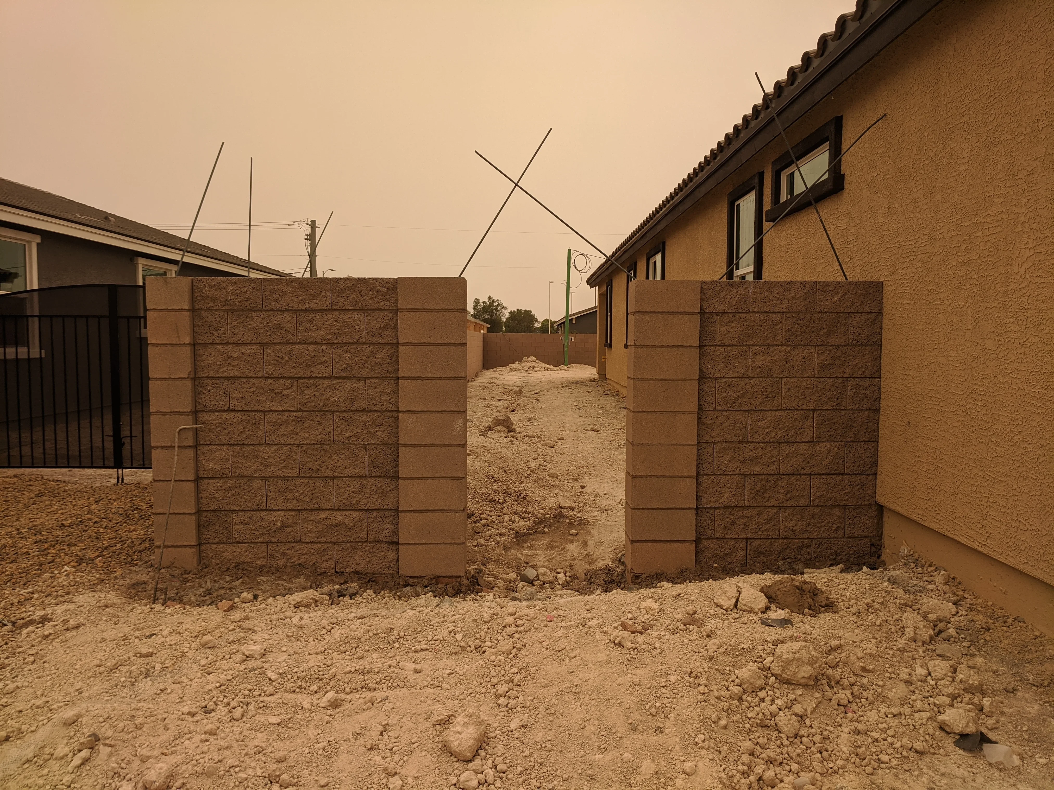 Brick masonry perimeter walls with concrete columns flanking residential driveway entrance