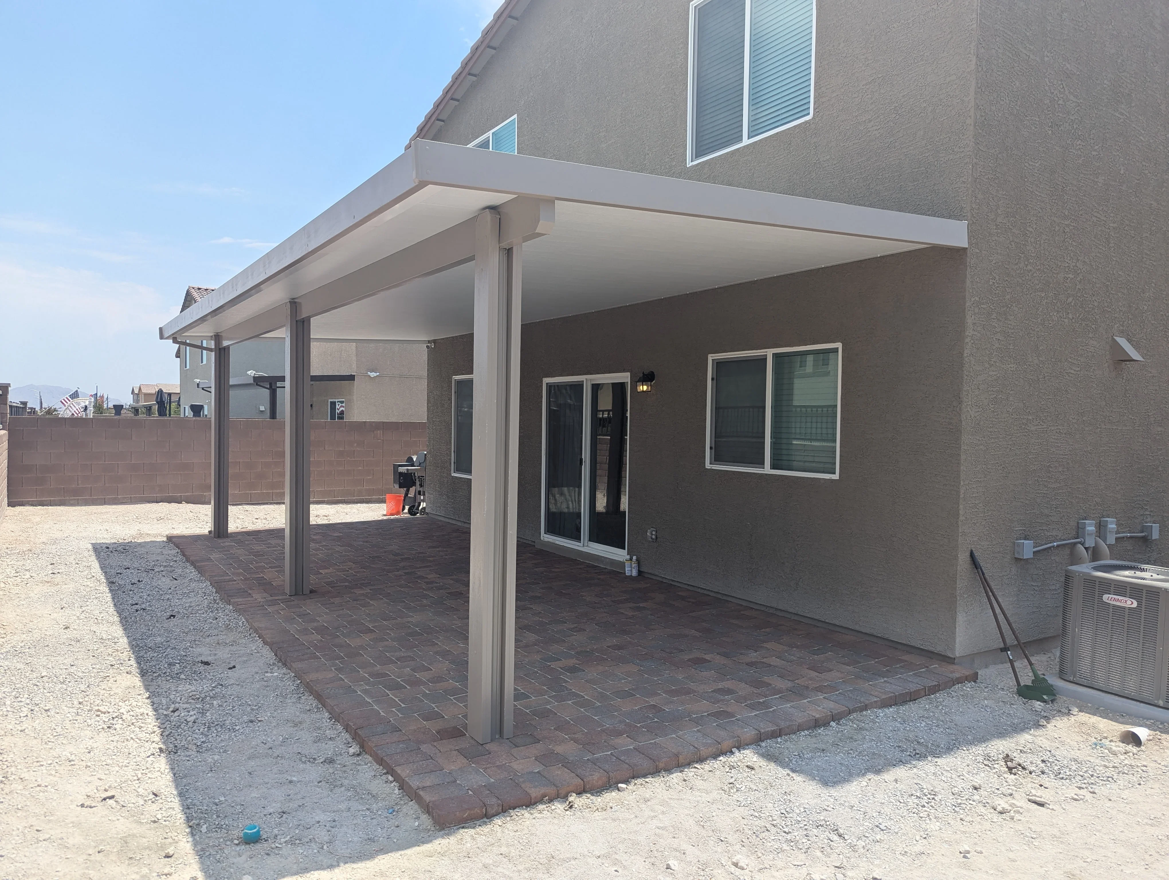 Modern aluminum patio cover with brick pavers and support columns on residential home