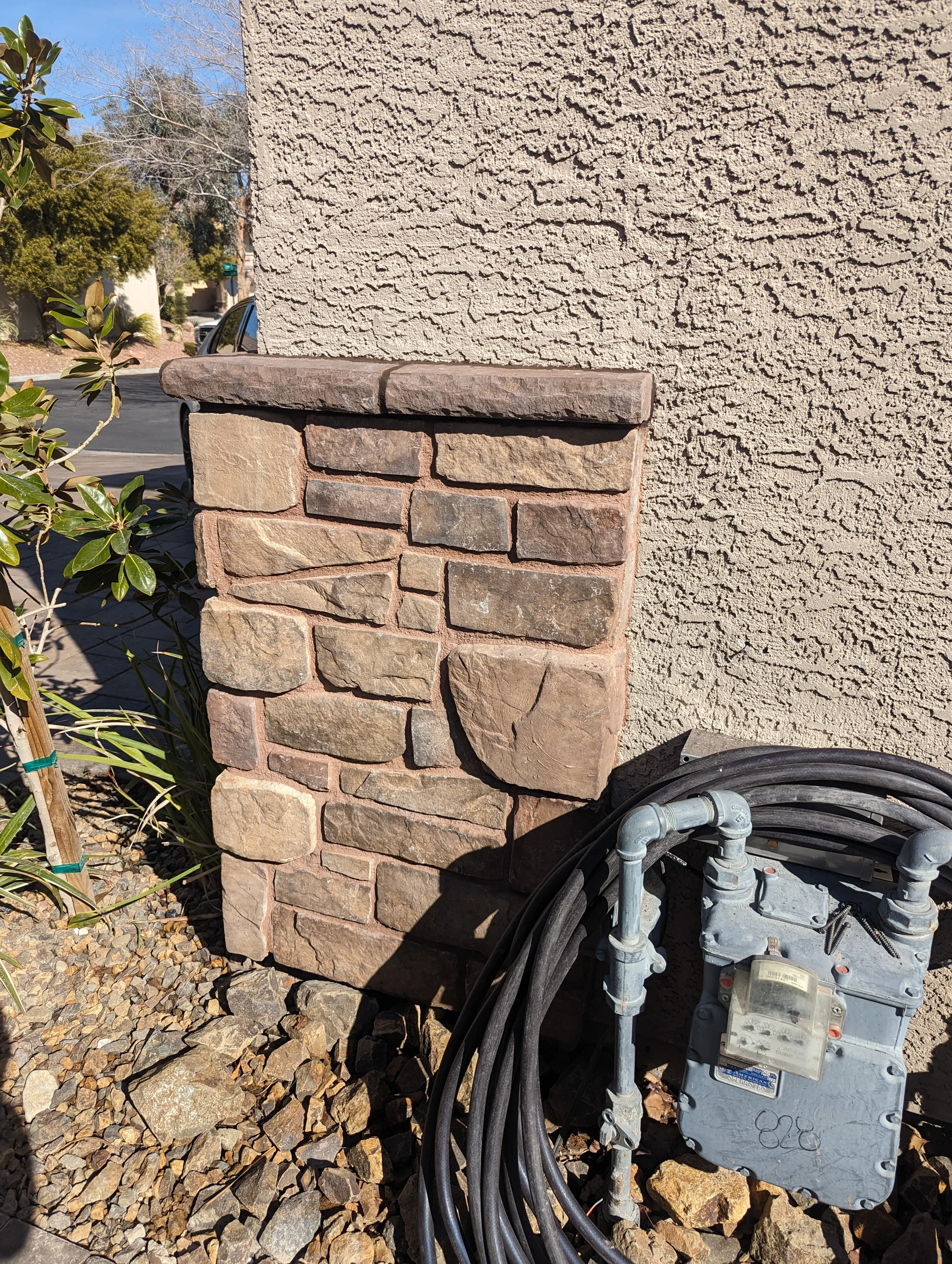 Stacked stone pillar with natural finish and utility box installation in Las Vegas