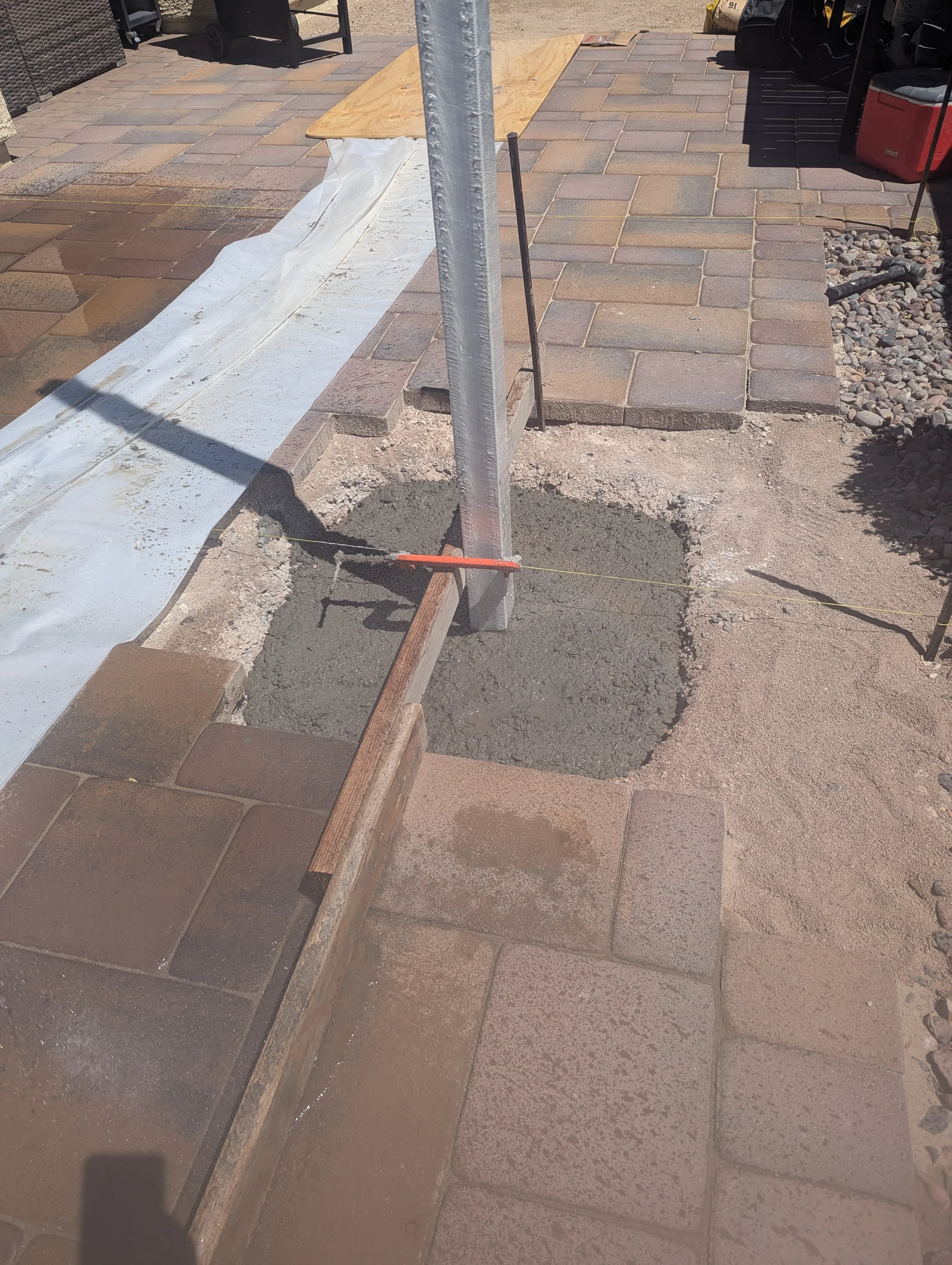 Patio construction in progress showing concrete pavers, edging, and drainage preparation